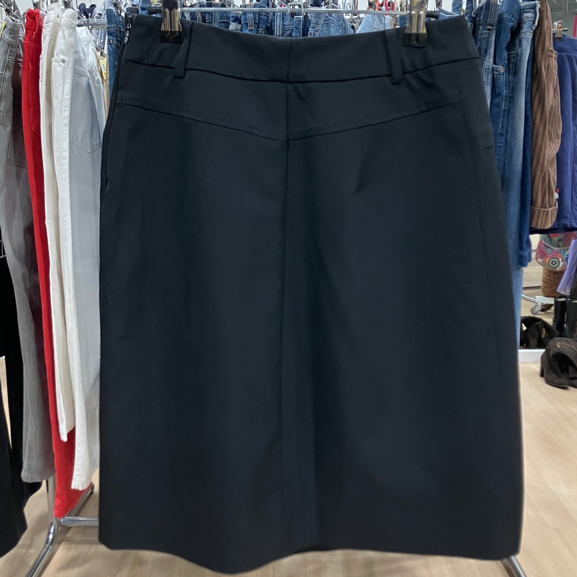 Black skirt hanging on a rack with other clothing in the background