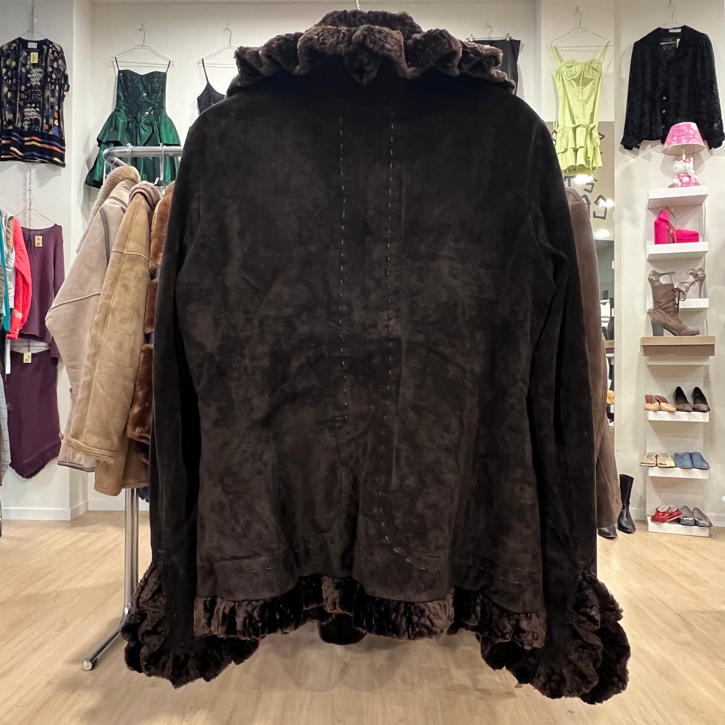 Dark brown coat with ruffled trim hanging in a store setting