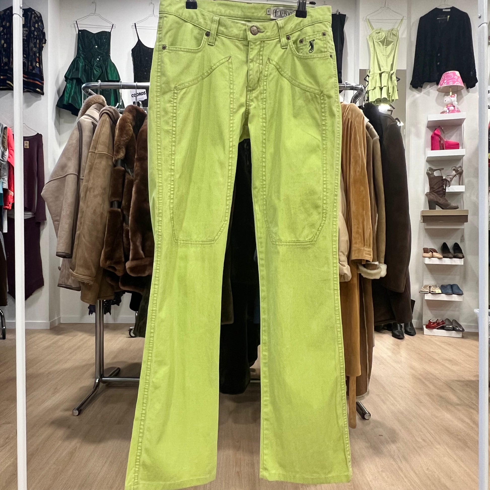 Bright green pants hanging in a clothing store with various garments in the background