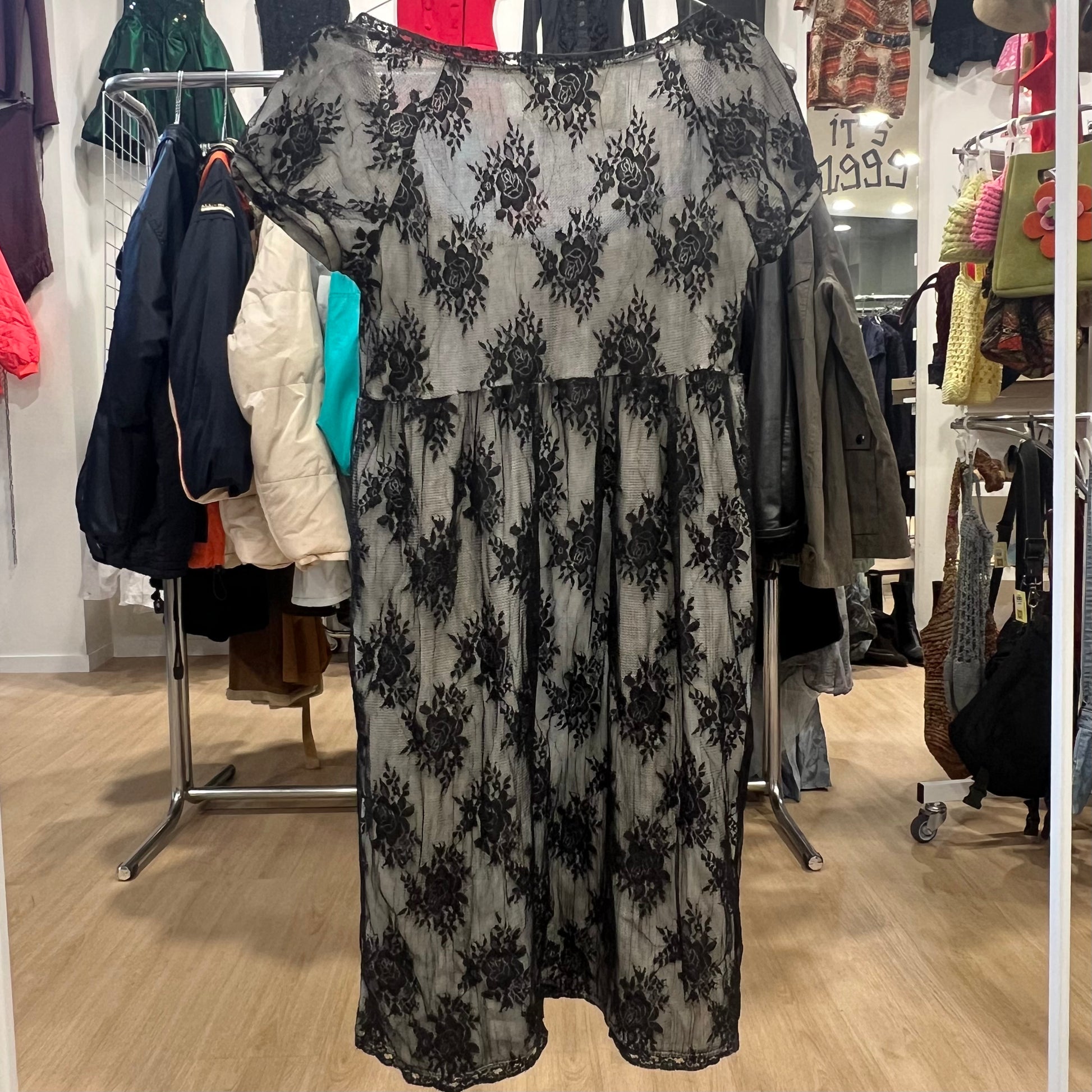 Black floral-patterned dress hanging in a store with various clothing items in the background