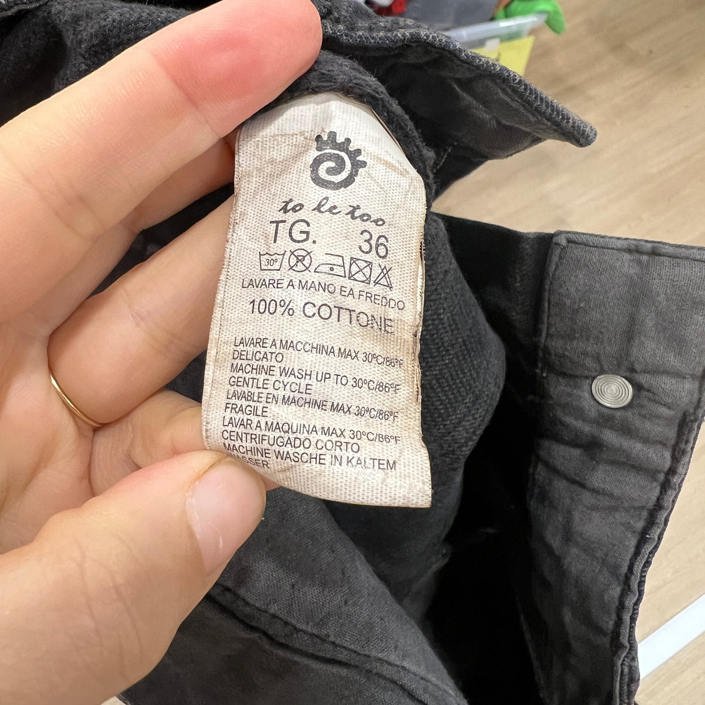 Clothing label on a black garment with text and symbols