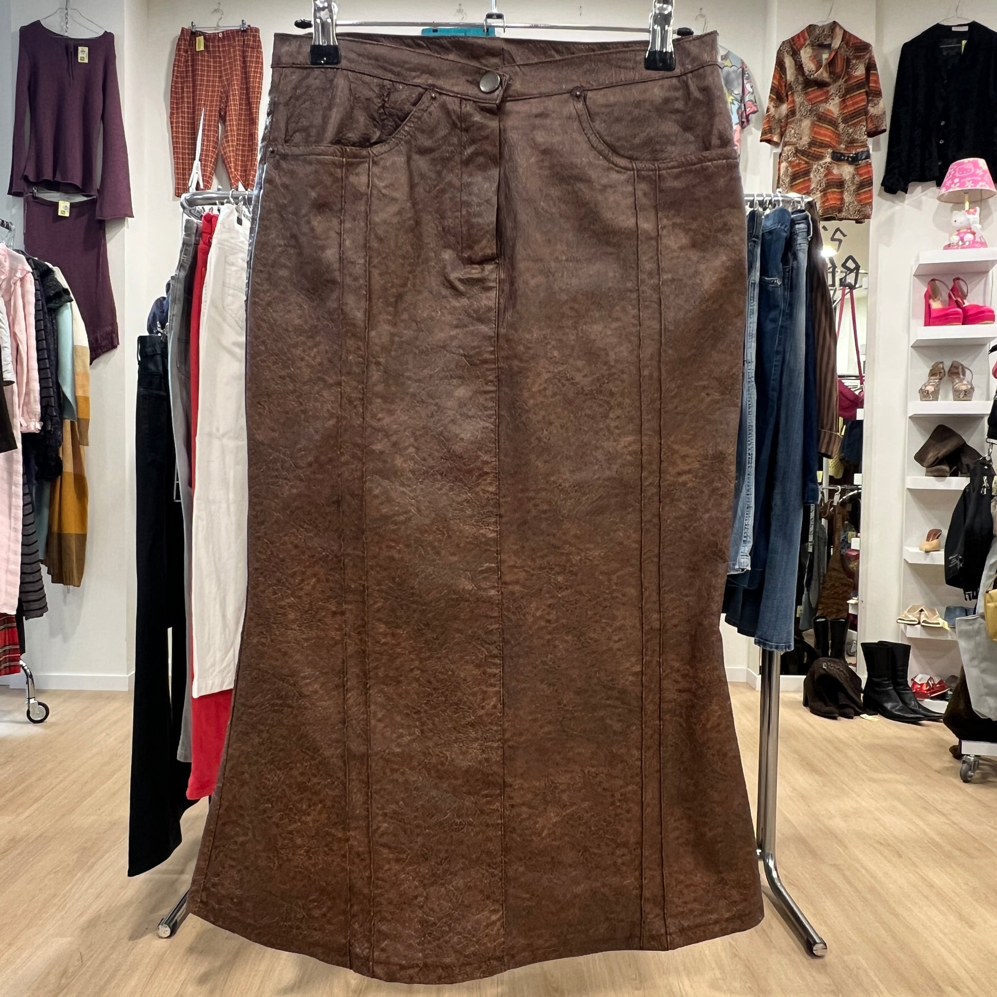 Brown skirt on a clothing rack in a store setting with various clothes in the background