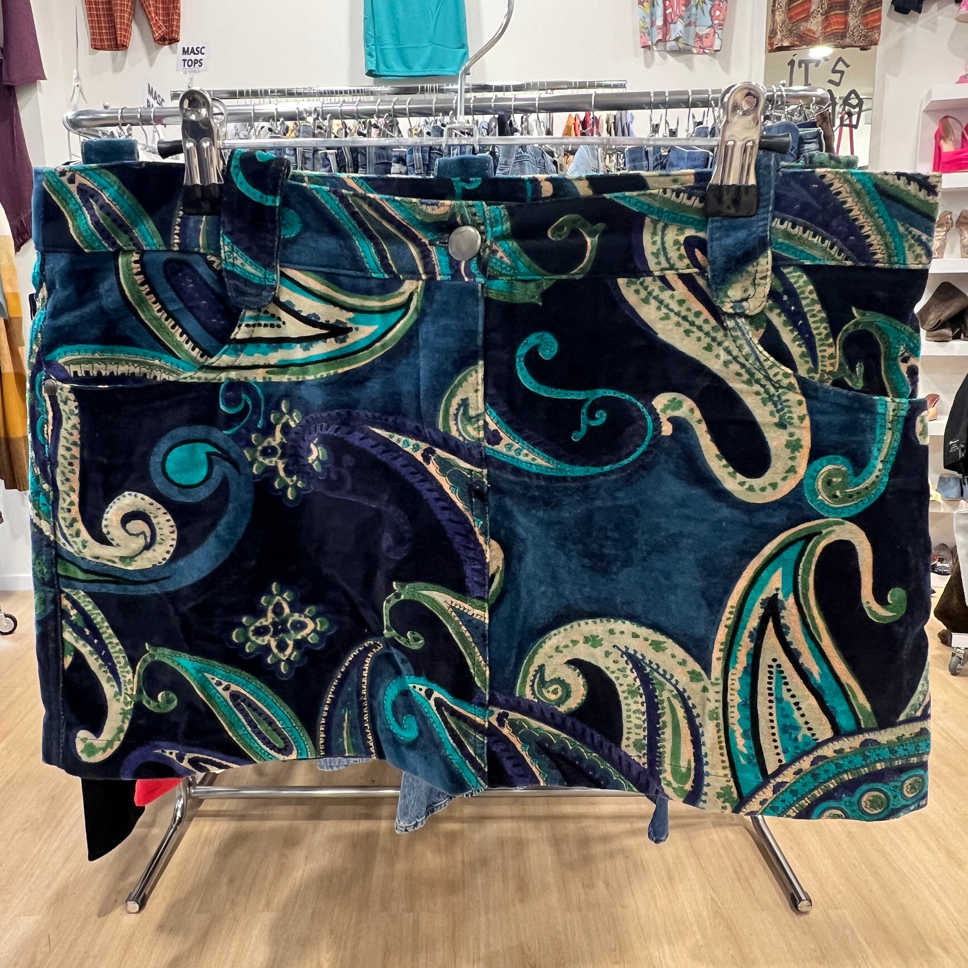 Blue skirt with intricate green and white patterns on a clothing rack