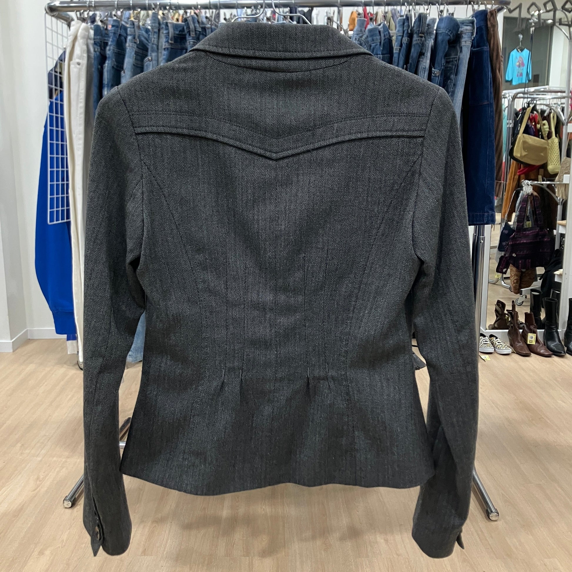 Dark gray jacket on a rack with clothing in the background
