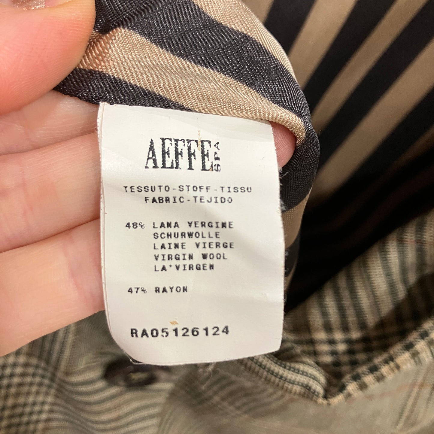 Fabric label with 'Aeffe' branding and material information on a plaid fabric background