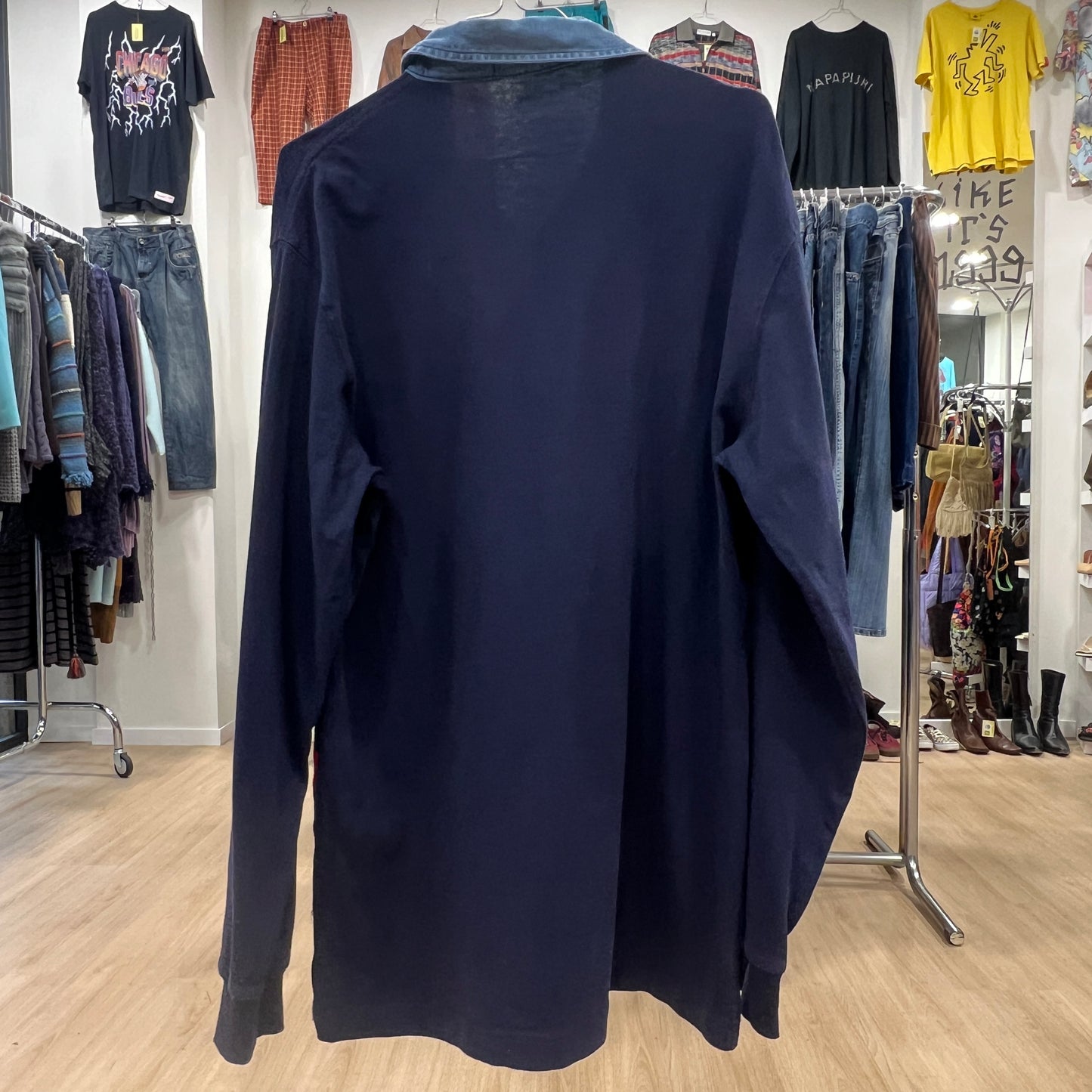 Navy blue sweater on a hanger in a clothing store setting