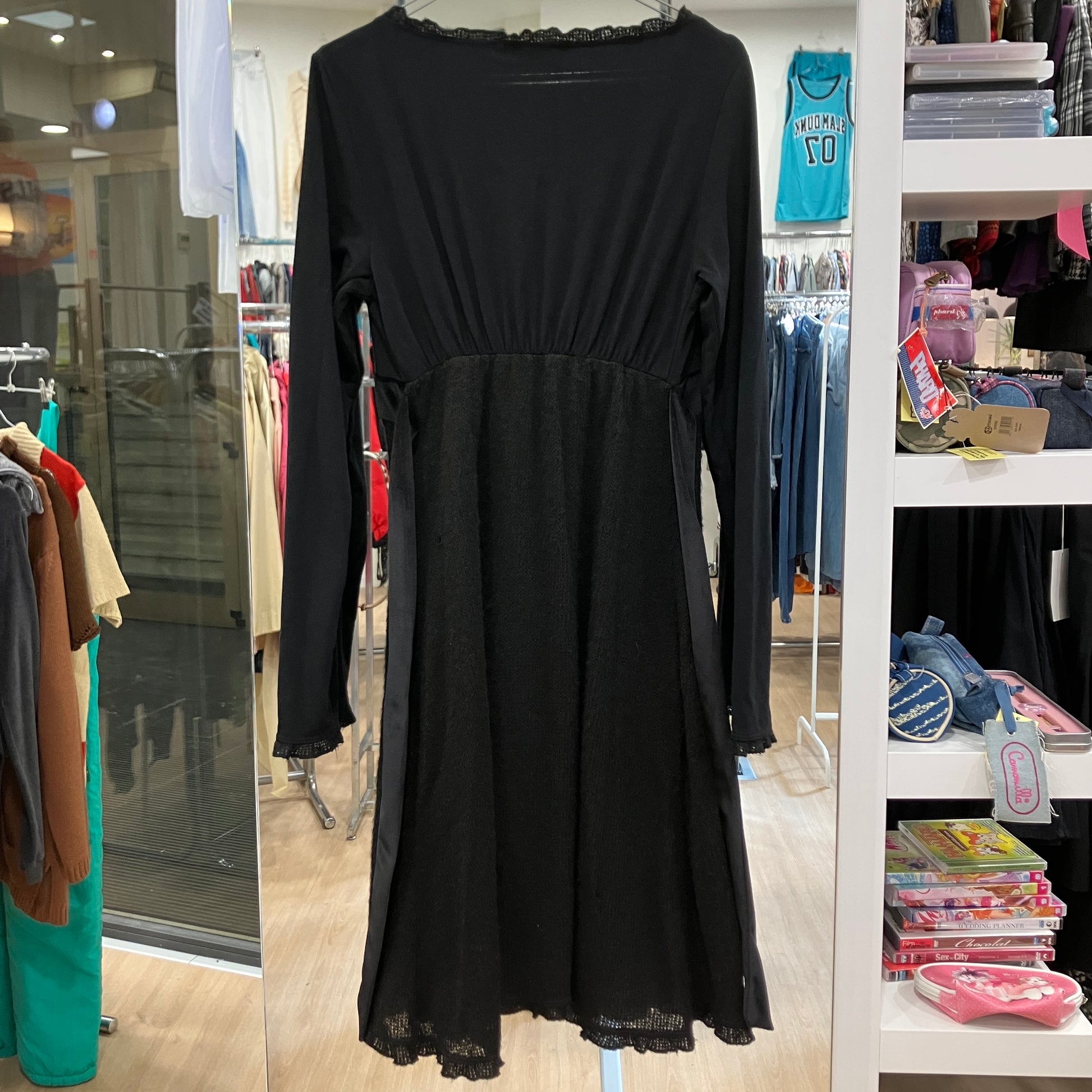 Black dress on a rack in a store setting with various items in the background