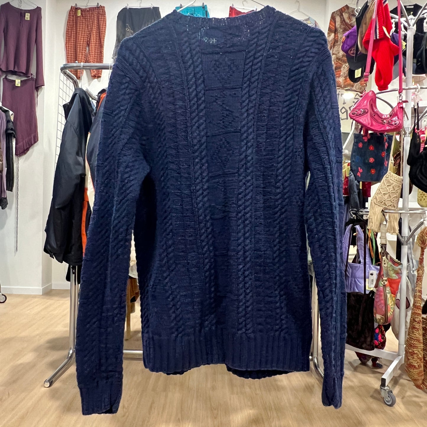 Navy blue cable knit sweater on a rack with a store background