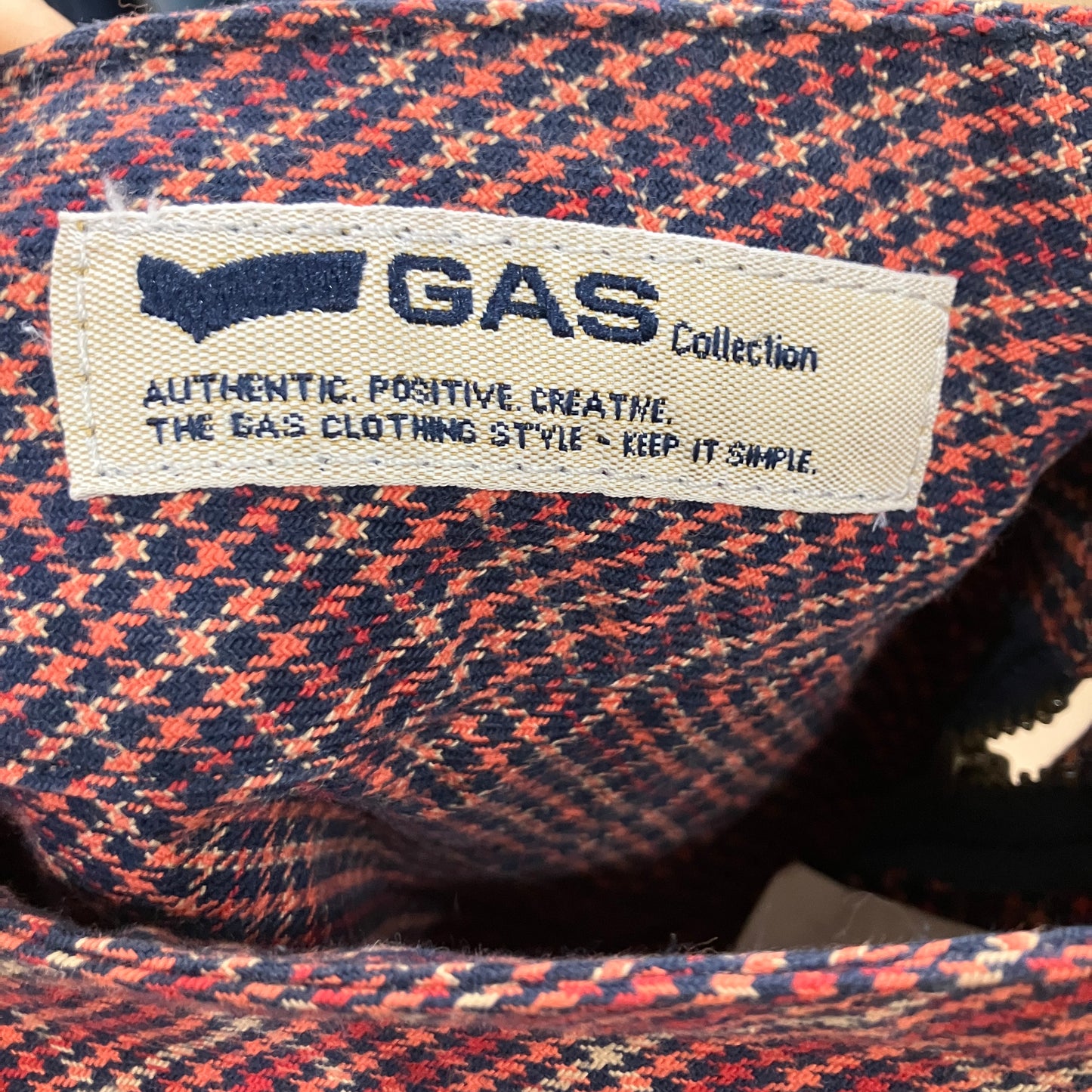 Close-up of a GAS Collection label on a houndstooth patterned fabric