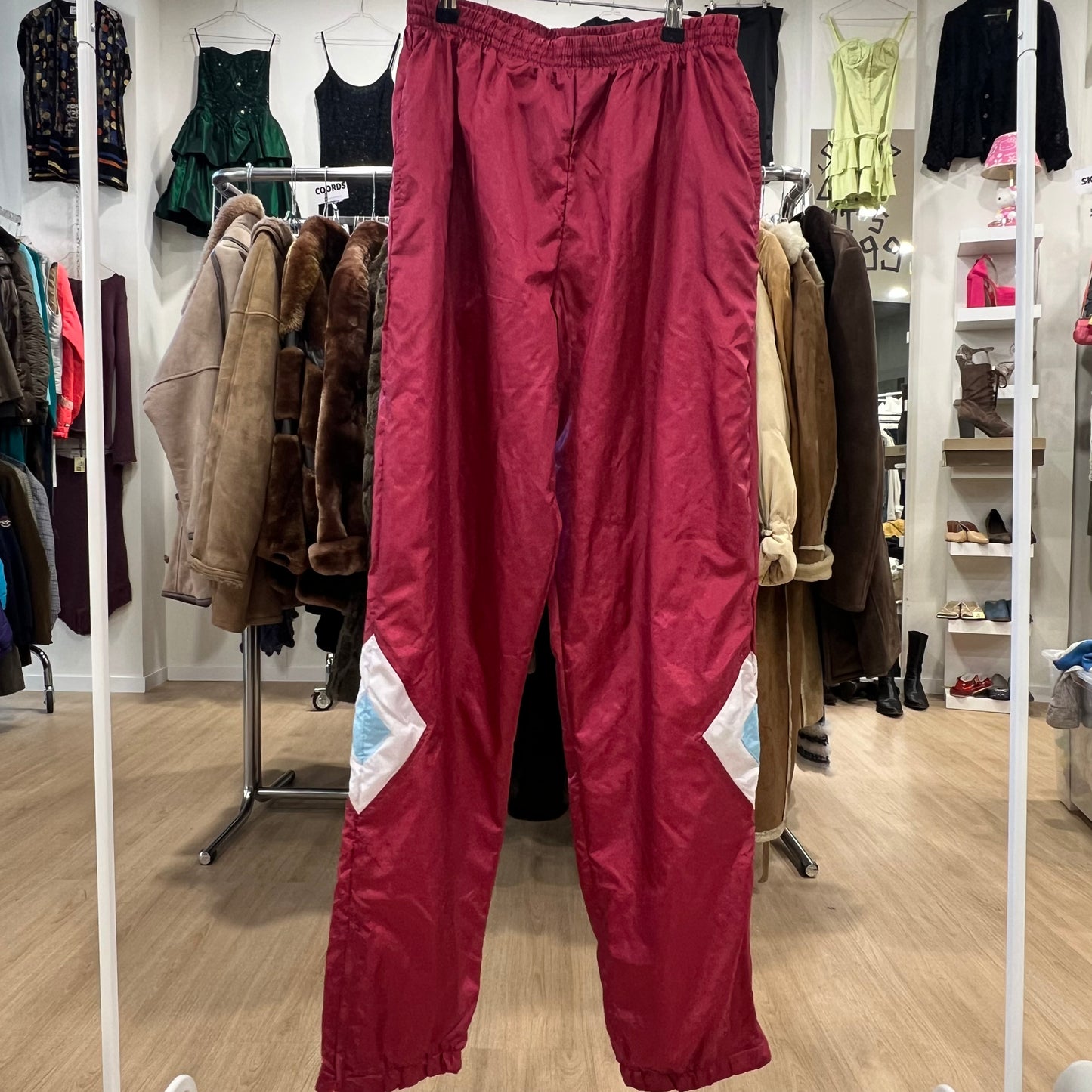 Red pants hanging in a clothing store with various garments in the background