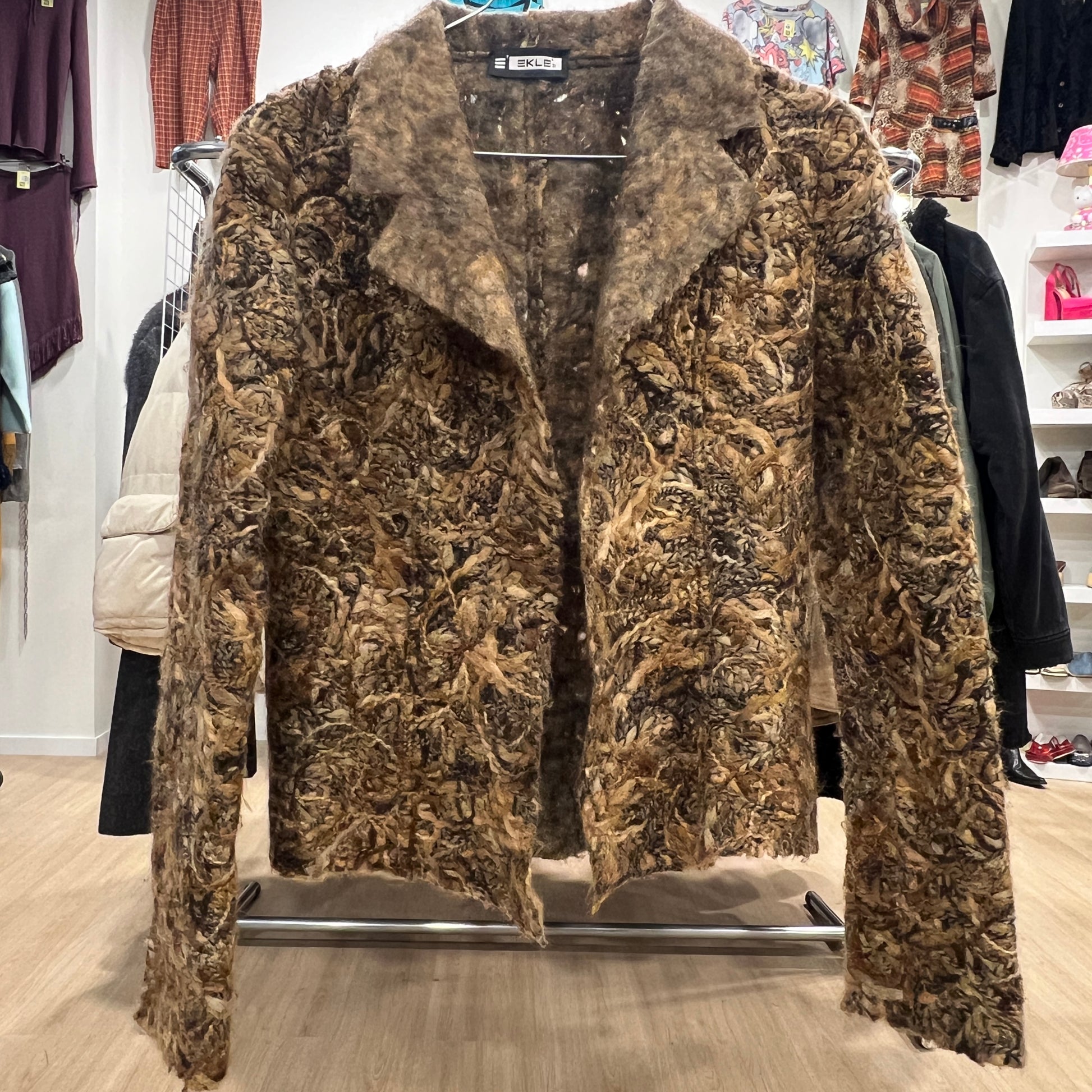 Brown textured coat on a hanger in a store setting
