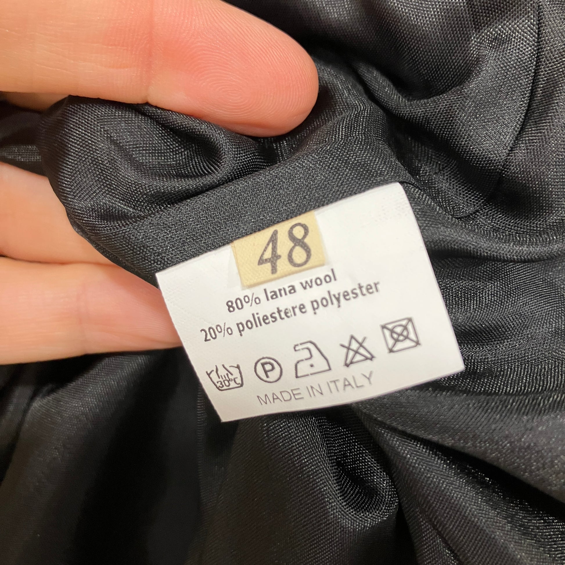 Clothing label on gray fabric with size 48 and material details