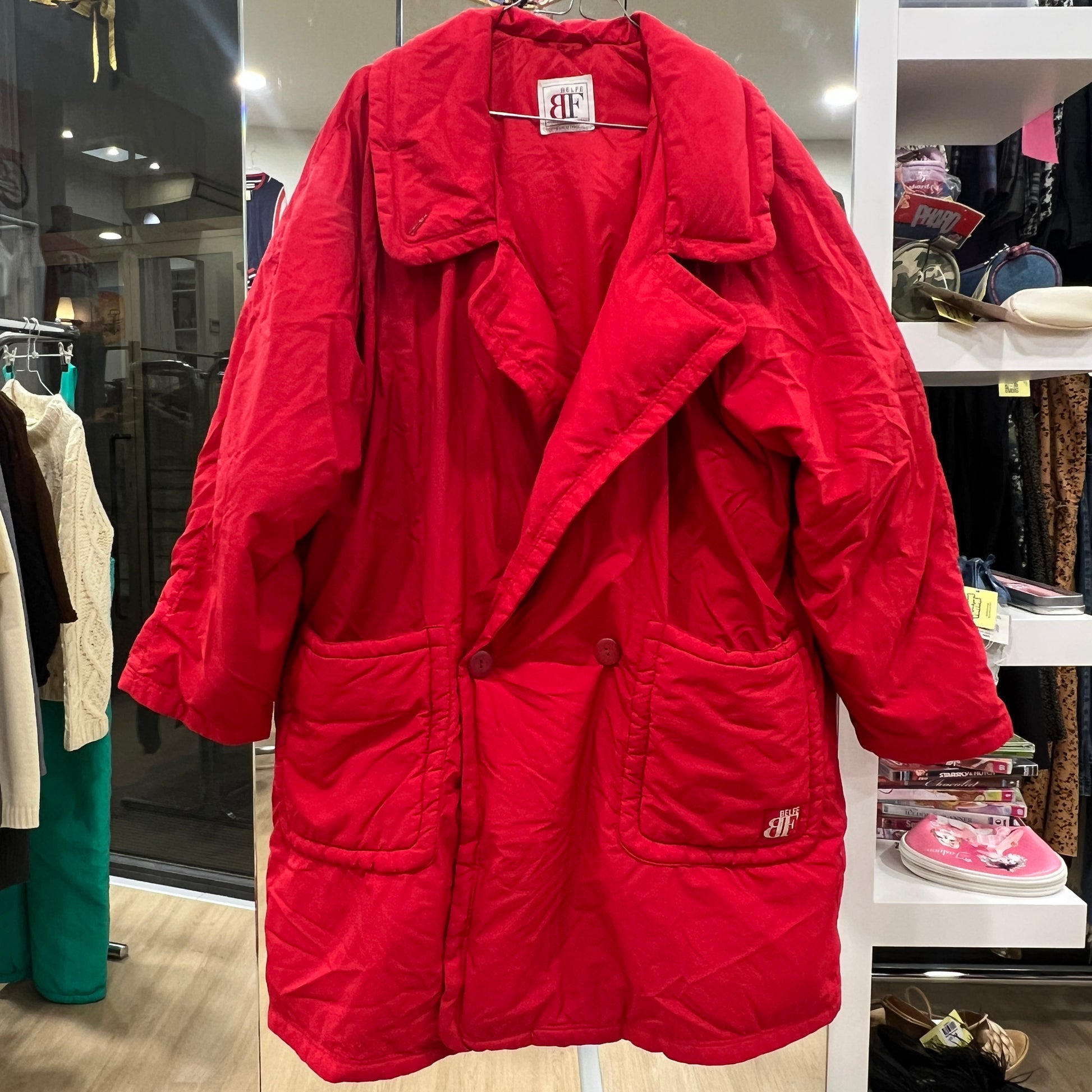 Red coat with brand logo on a rack in a store setting