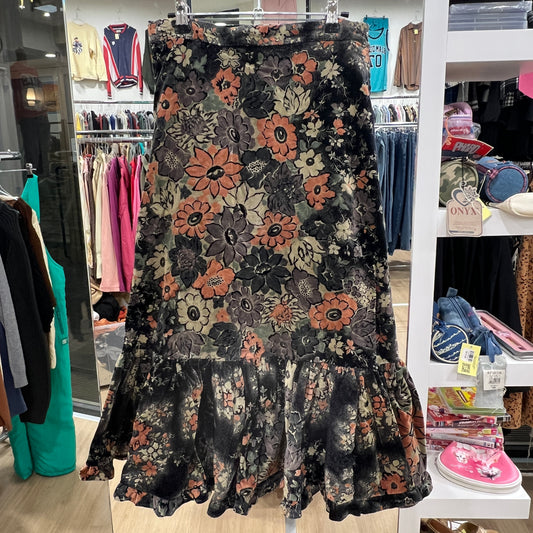 Floral patterned skirt hanging in a store with clothing racks and shelves in the background