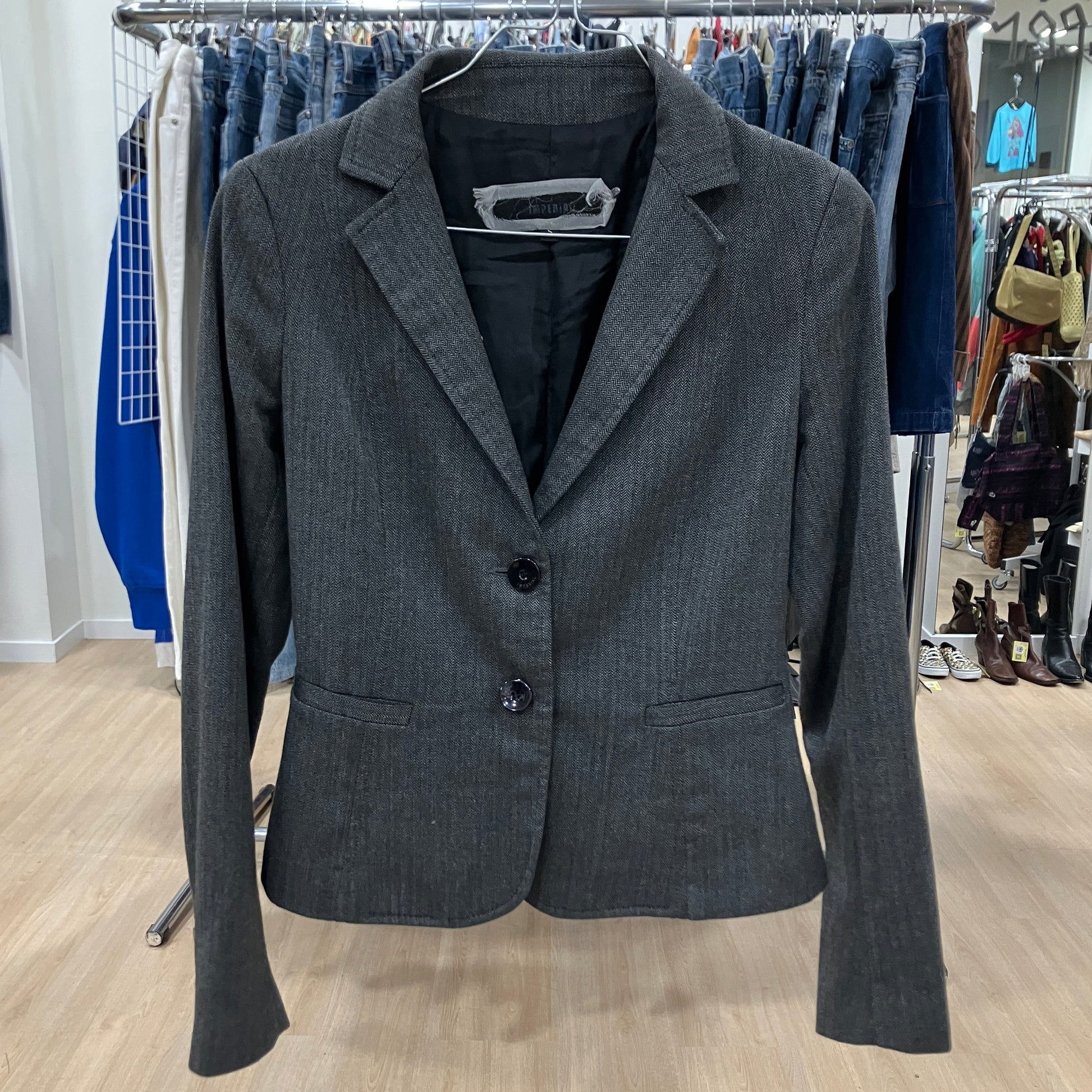 Gray blazer on a hanger with clothing racks in the background