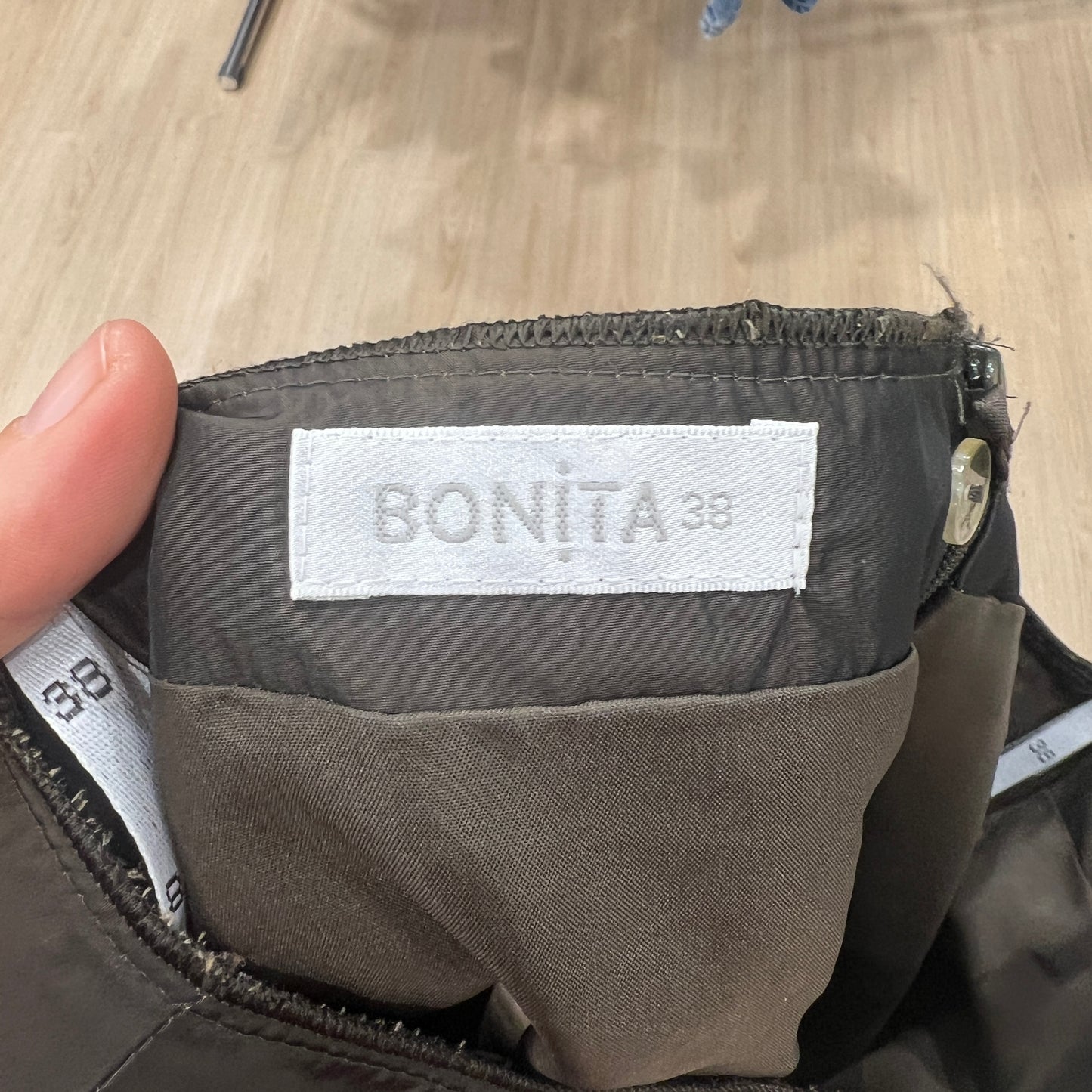 Close-up of a 'BONITA 38' label on a piece of clothing with a wooden surface in the background
