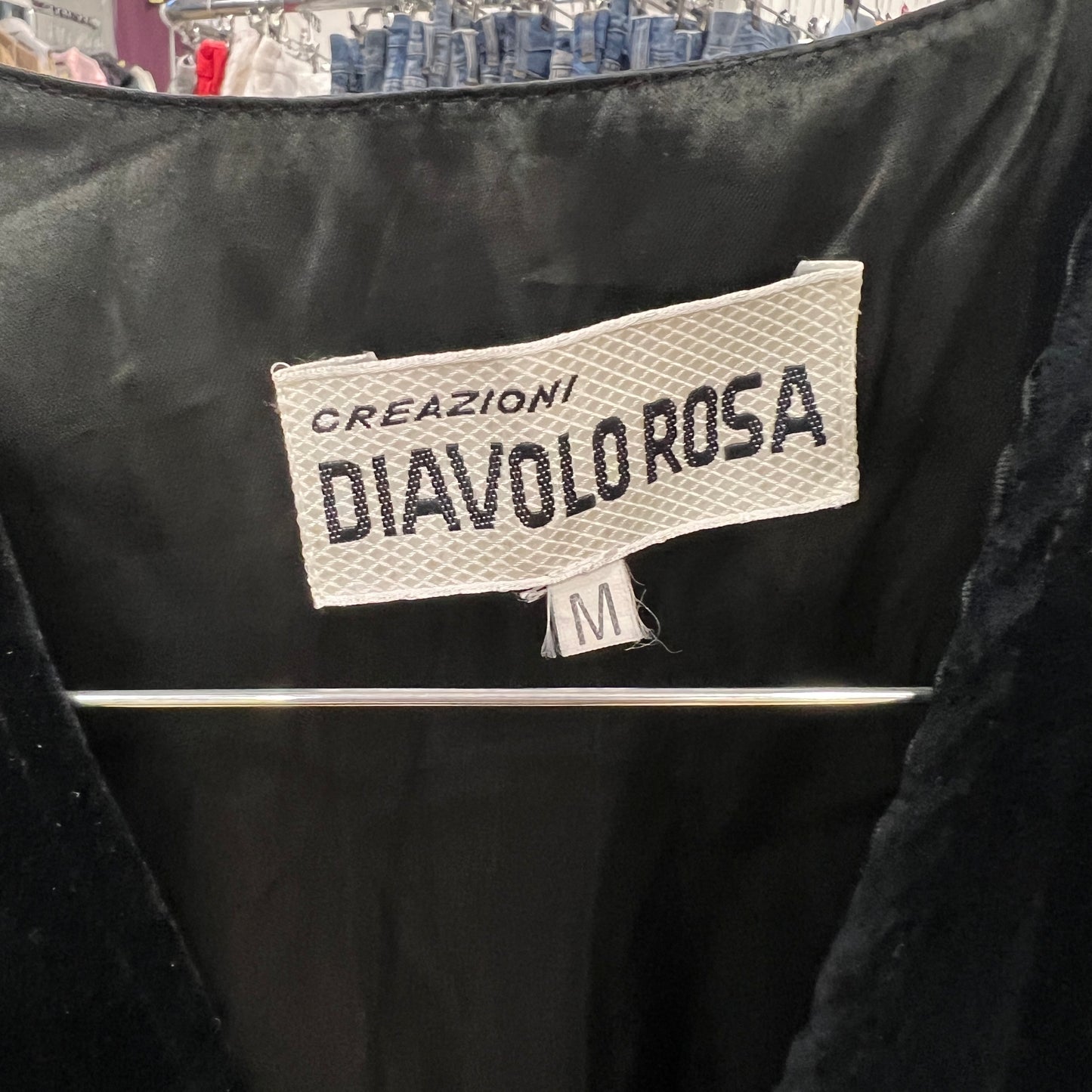 Black garment with 'Creazioni Diavolo Rosa' label on a blurred background