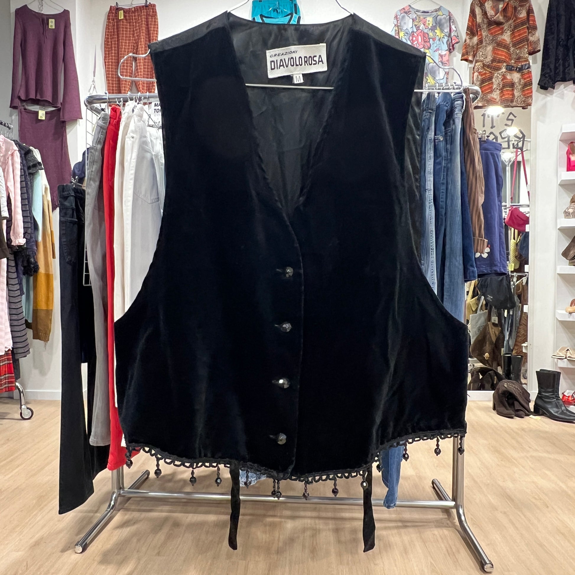 Black vest on a rack in a clothing store with various garments in the background
