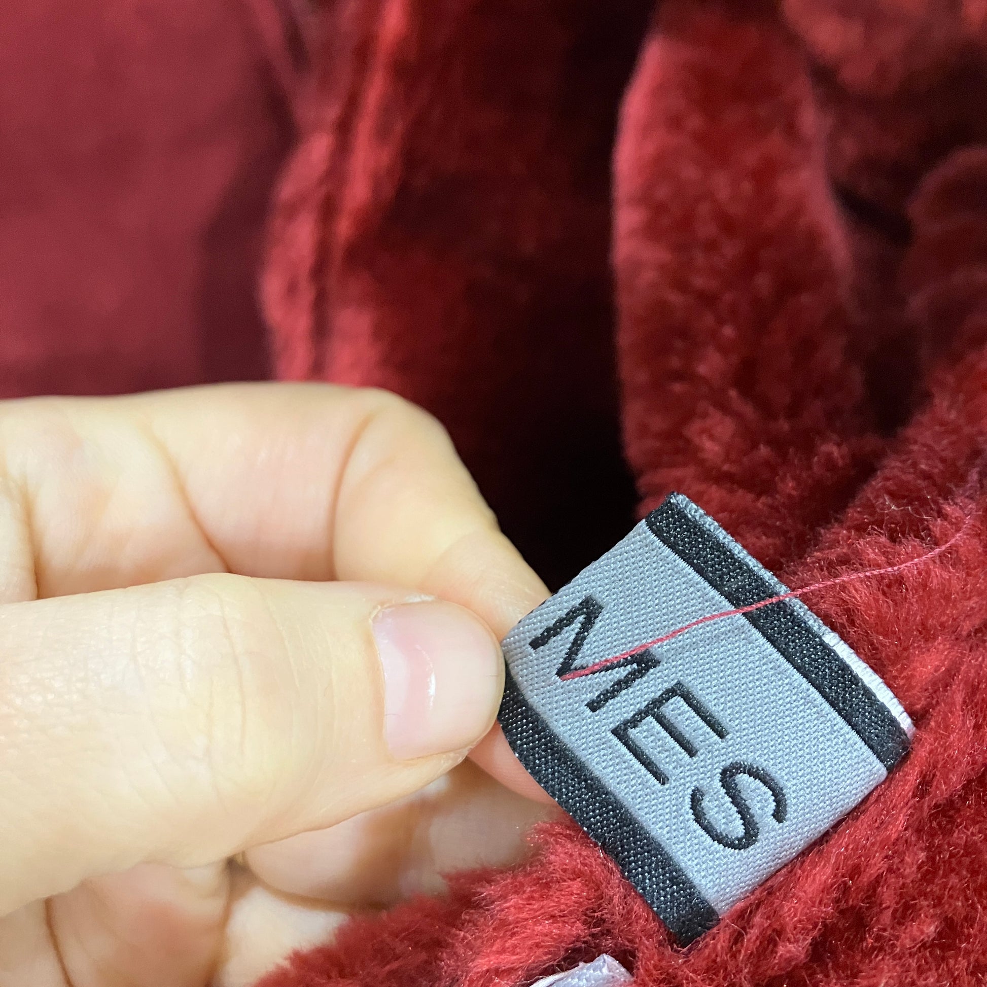 Close-up of a red textured fabric with a brand label 'MES'