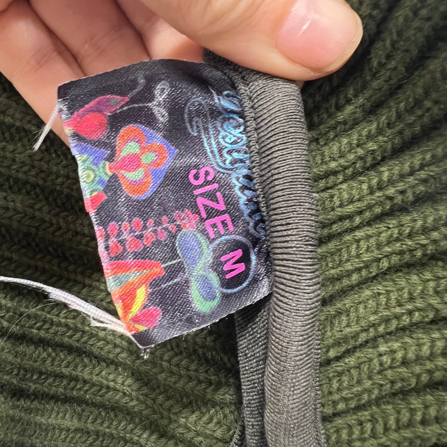 Close-up of a size label on a green knitted garment