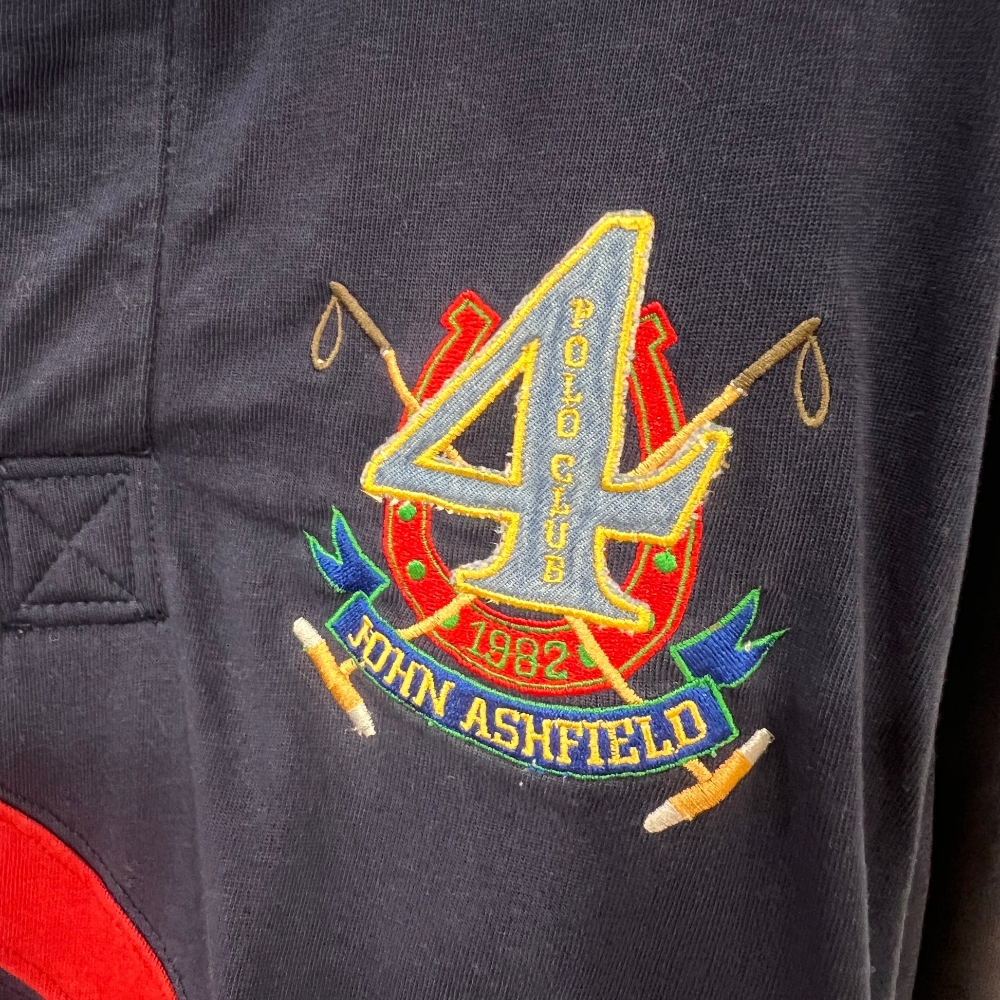Embroidered logo on a dark fabric with 'John Ashfield' text