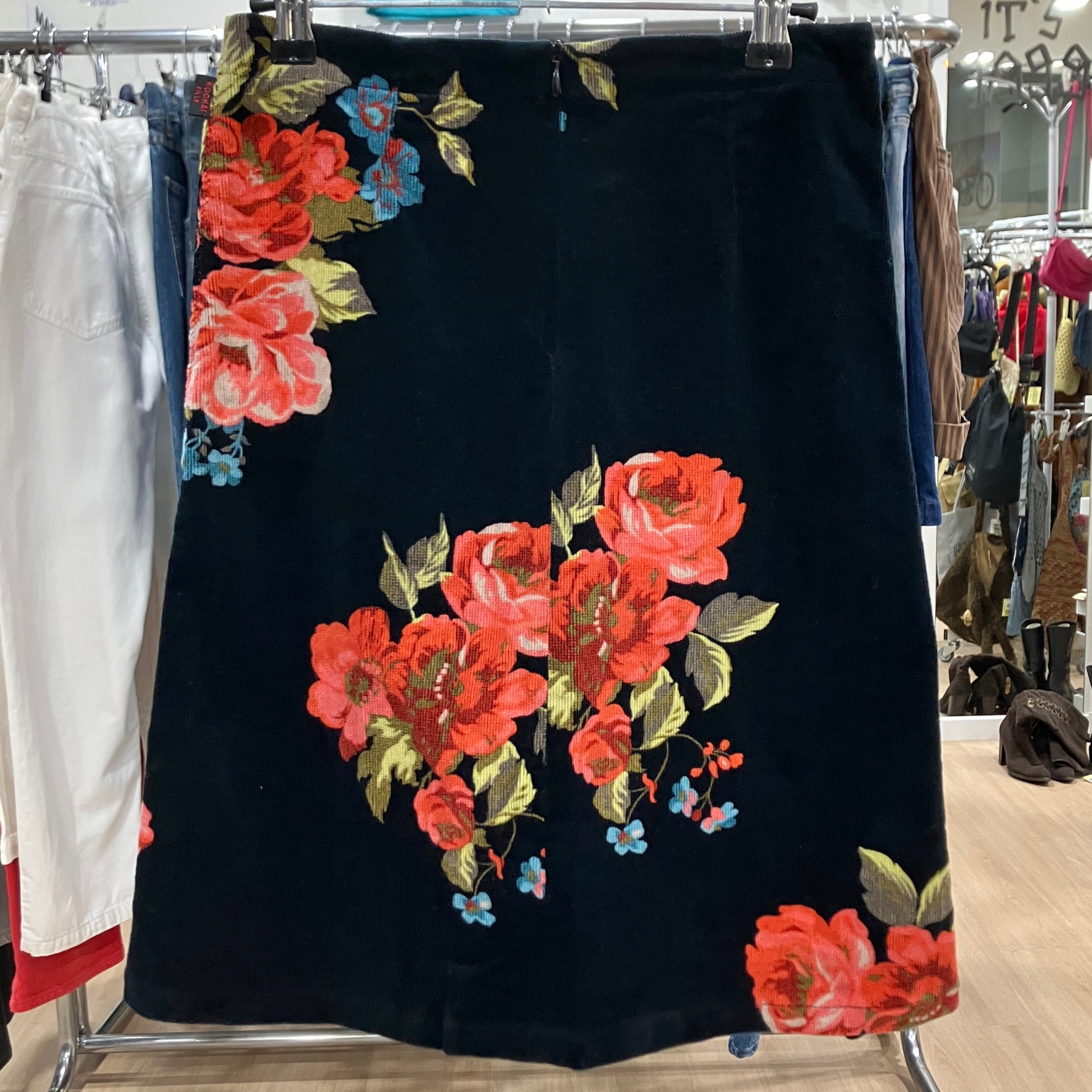 Black skirt with red floral pattern on a clothing rack