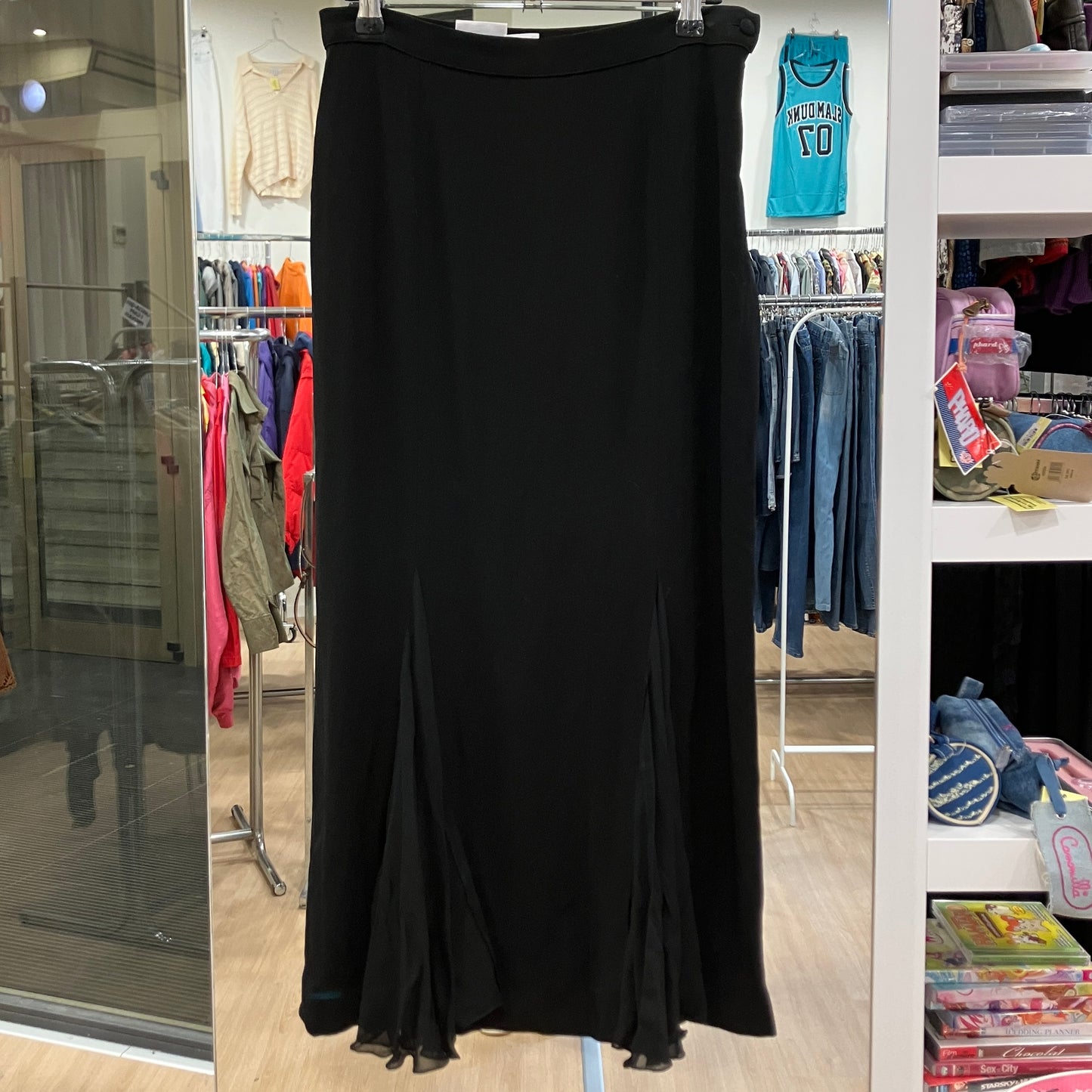 Black skirt hanging in a store with clothing racks and shelves in the background