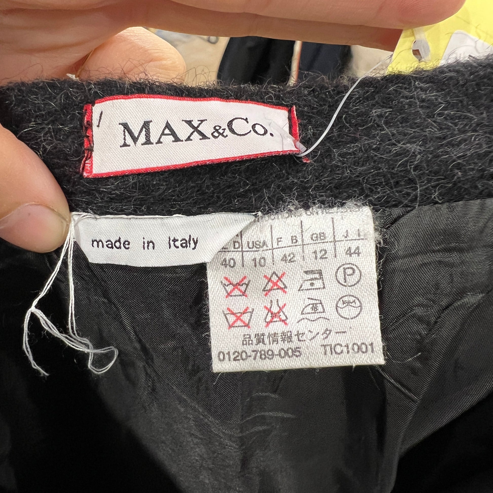 Clothing label with 'MAX&Co.' brand name and 'made in Italy' text on a textured fabric background