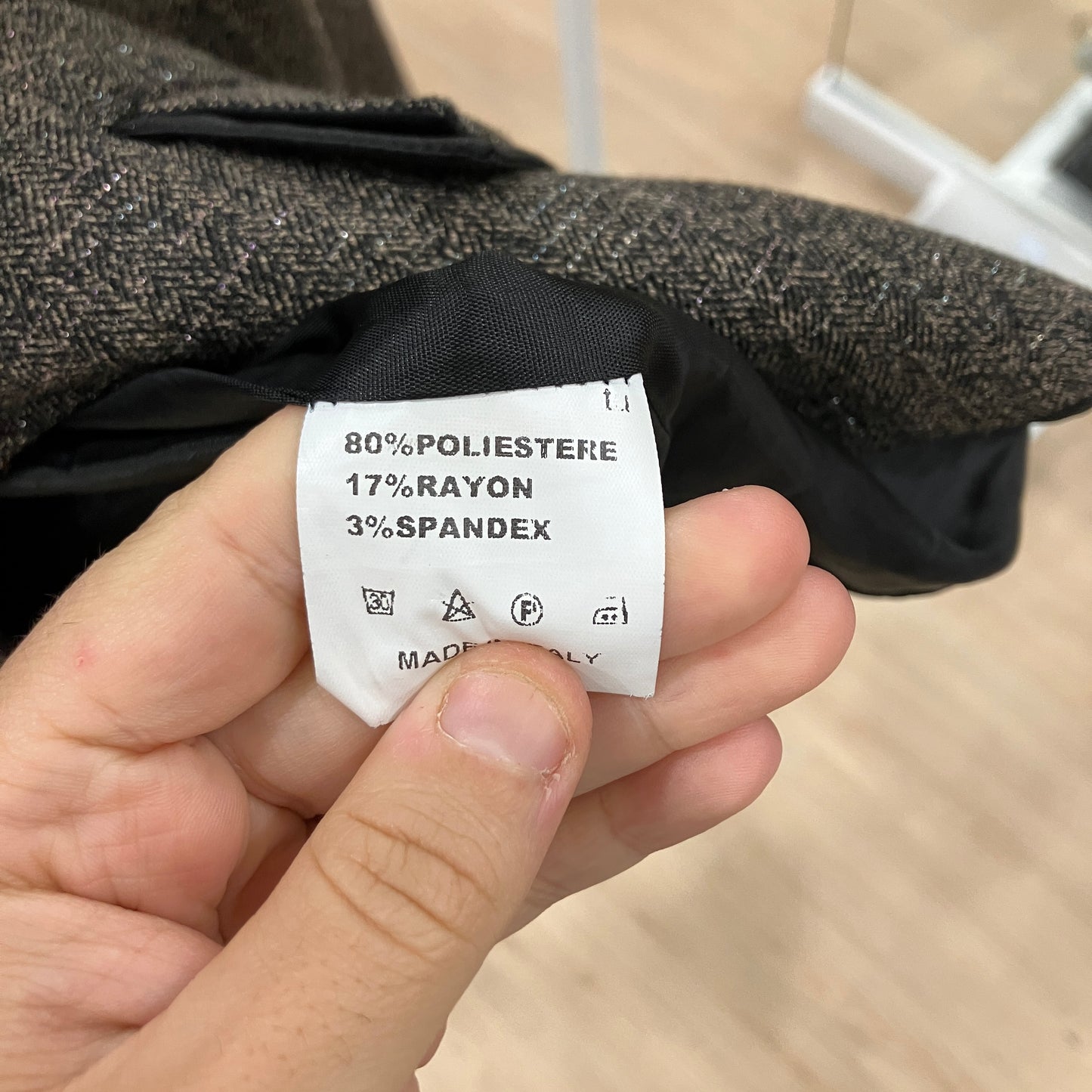 Clothing label with fabric composition details held by a hand