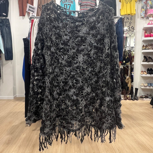 Black lace top with fringe on a rack in a store setting
