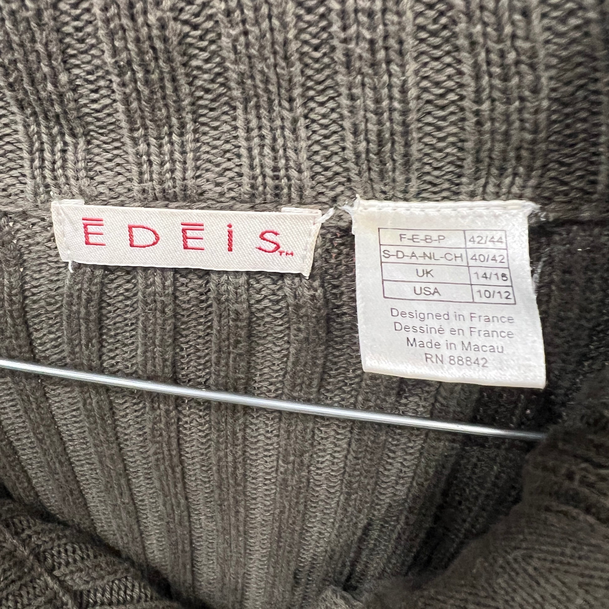 Close-up of a green knit sweater with 'EDEIS' label on a hanger