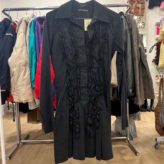 Black long-sleeve dress with a collared neckline, button-down front, and ruffled detailing along the placket, hanging on a rack in a clothing store