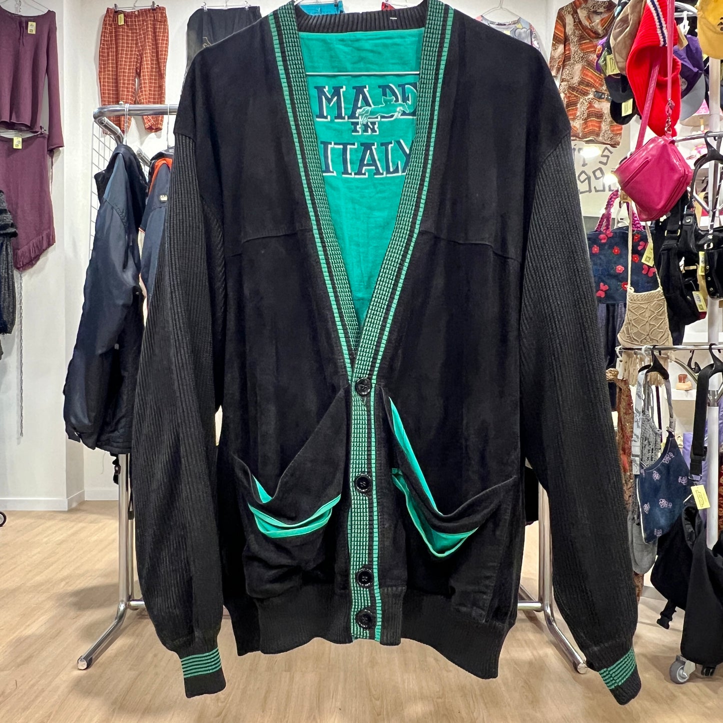 Black cardigan with green accents and 'Made in Italy' text displayed in a store setting