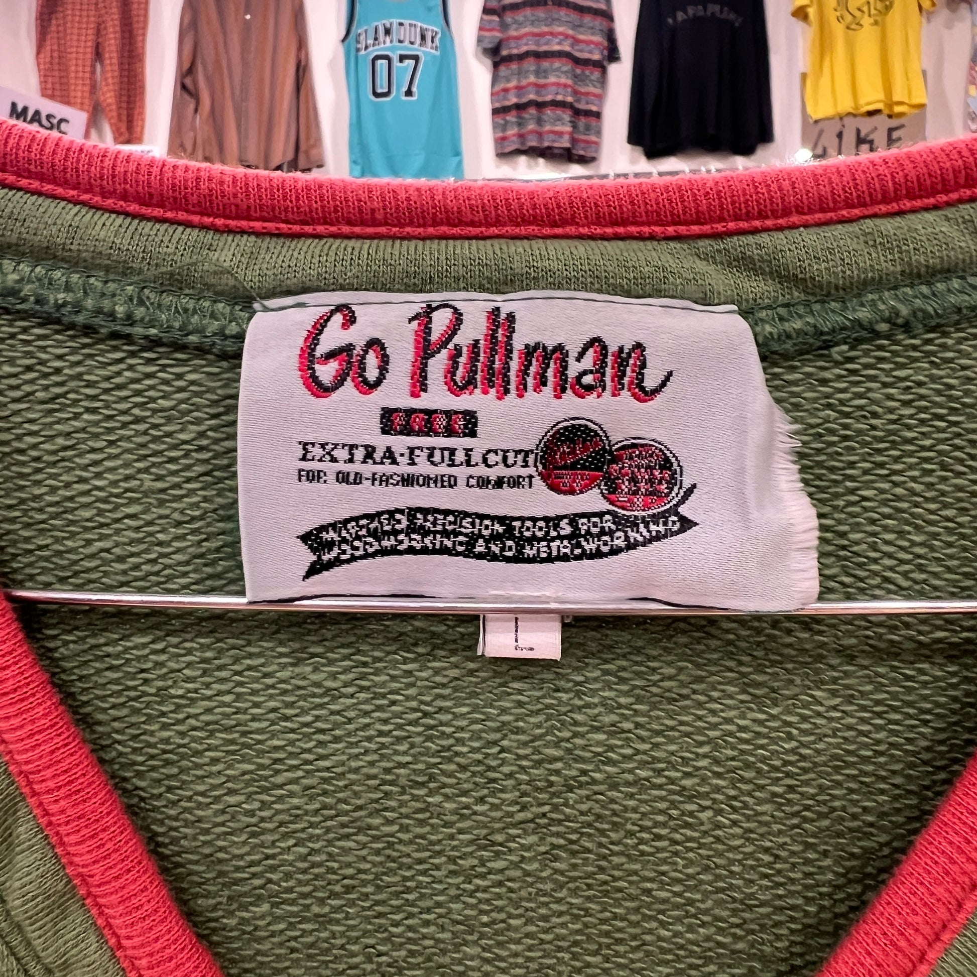 Close-up of a Go Pullman label on a green garment with red accents
