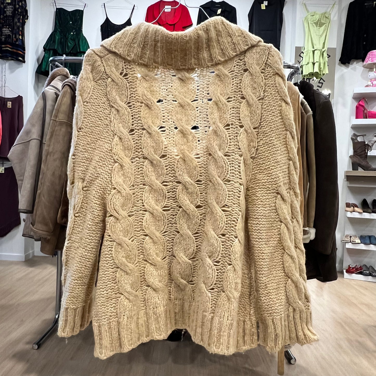 Beige cable knit sweater on a mannequin in a clothing store setting