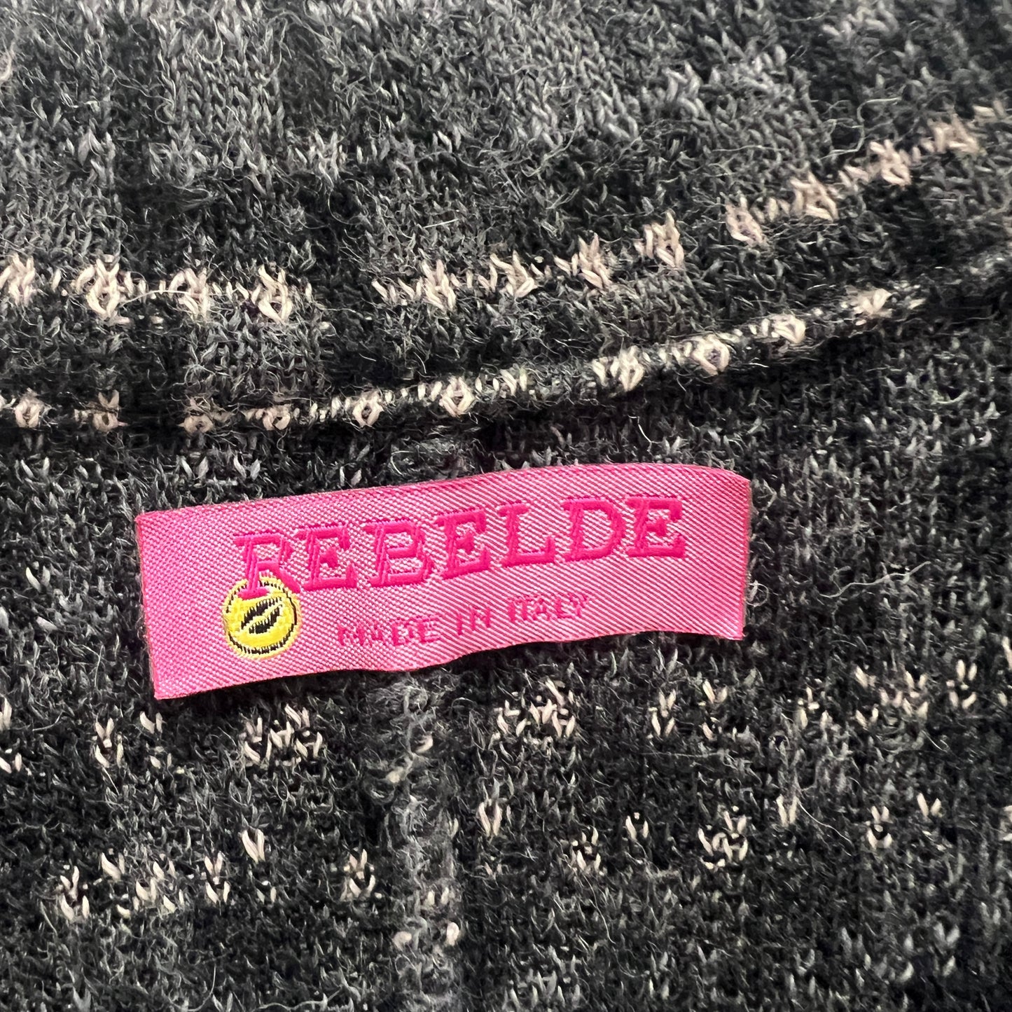 Pink label with 'REBELDE' text on a textured fabric background