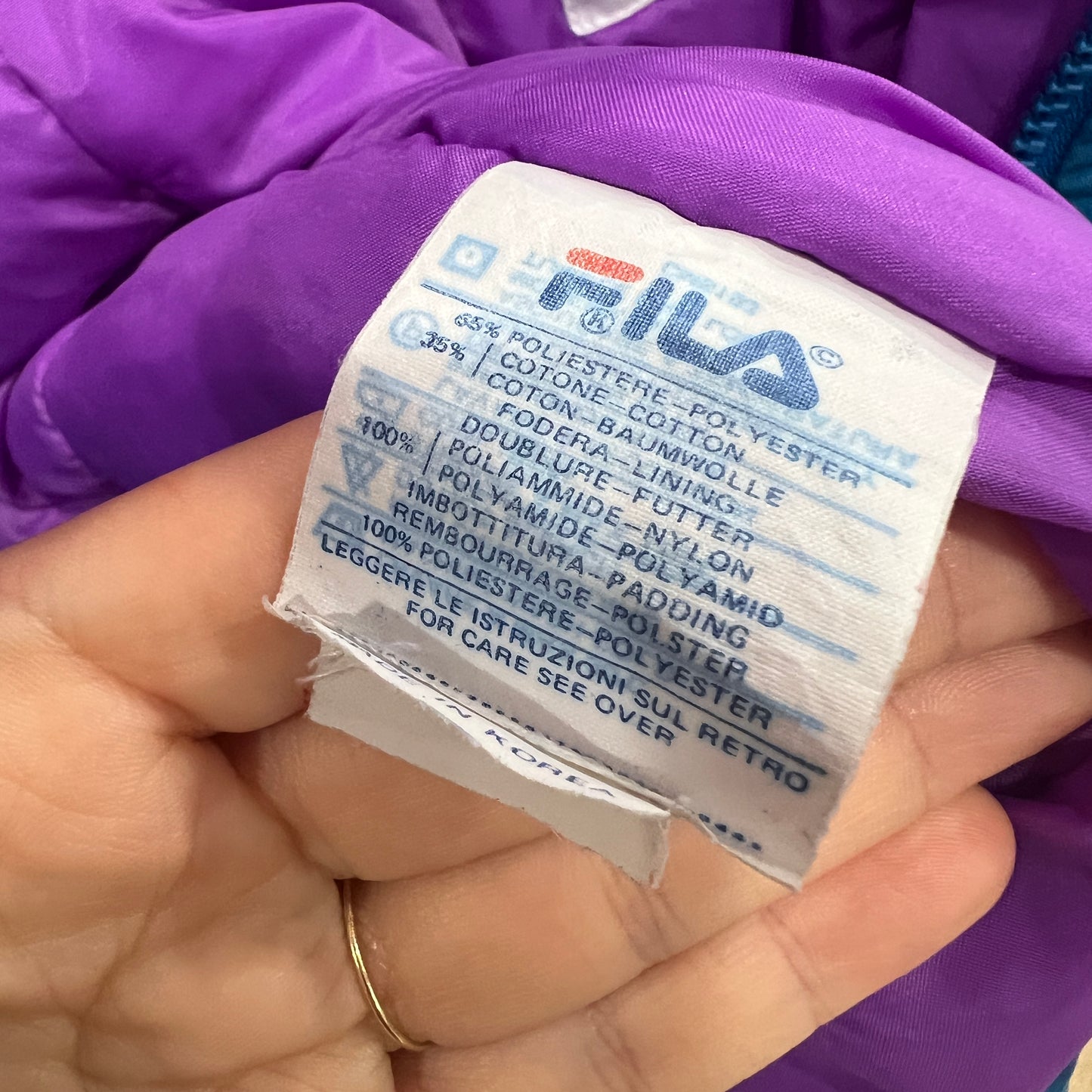 Hand holding a label with 'FILA' branding and text