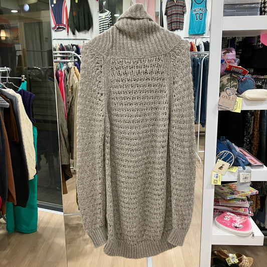 Gray knitted sweater on a hanger in a store setting with clothing racks and shelves in the background