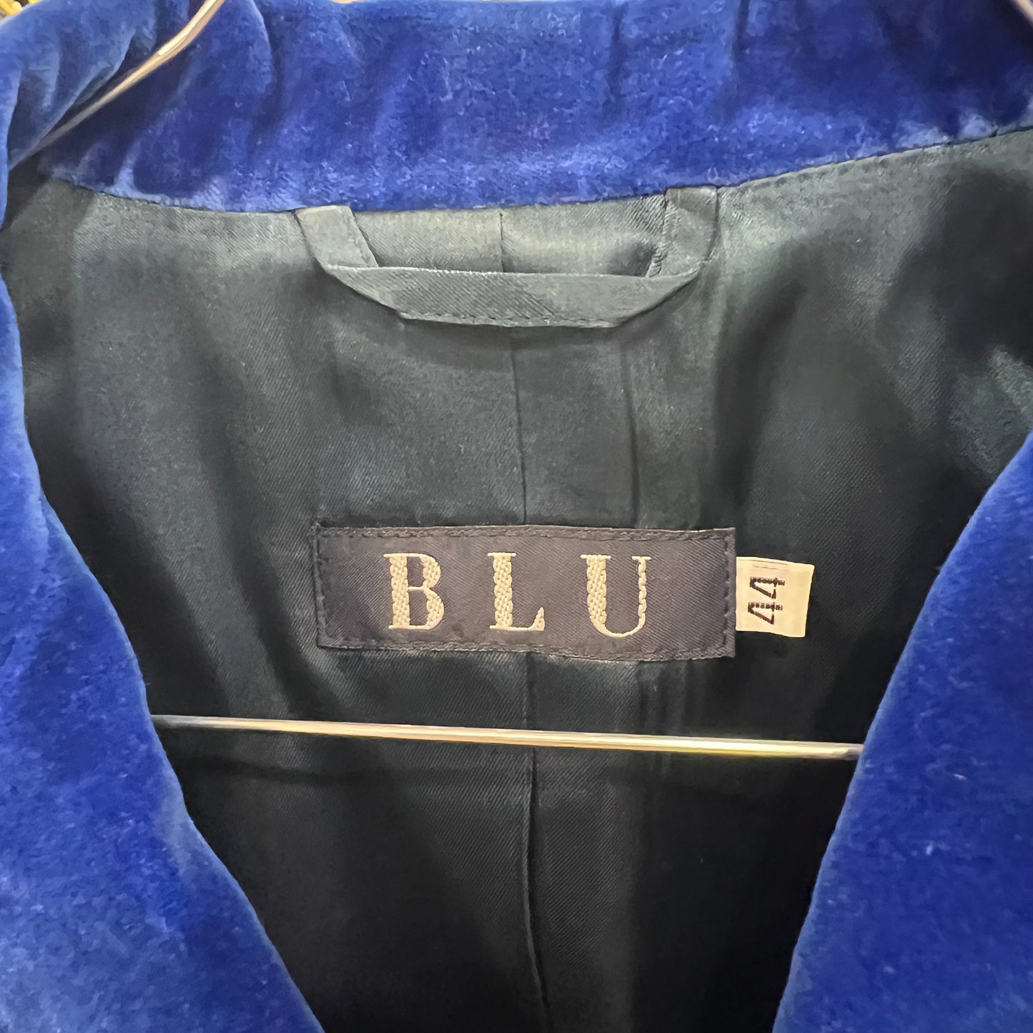 Black garment with 'BLU' label and size tag on a blue background