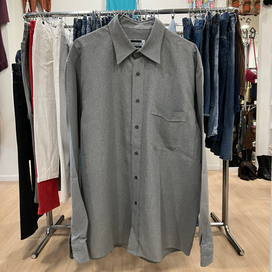 Gray button-up shirt on a rack with clothing in the background