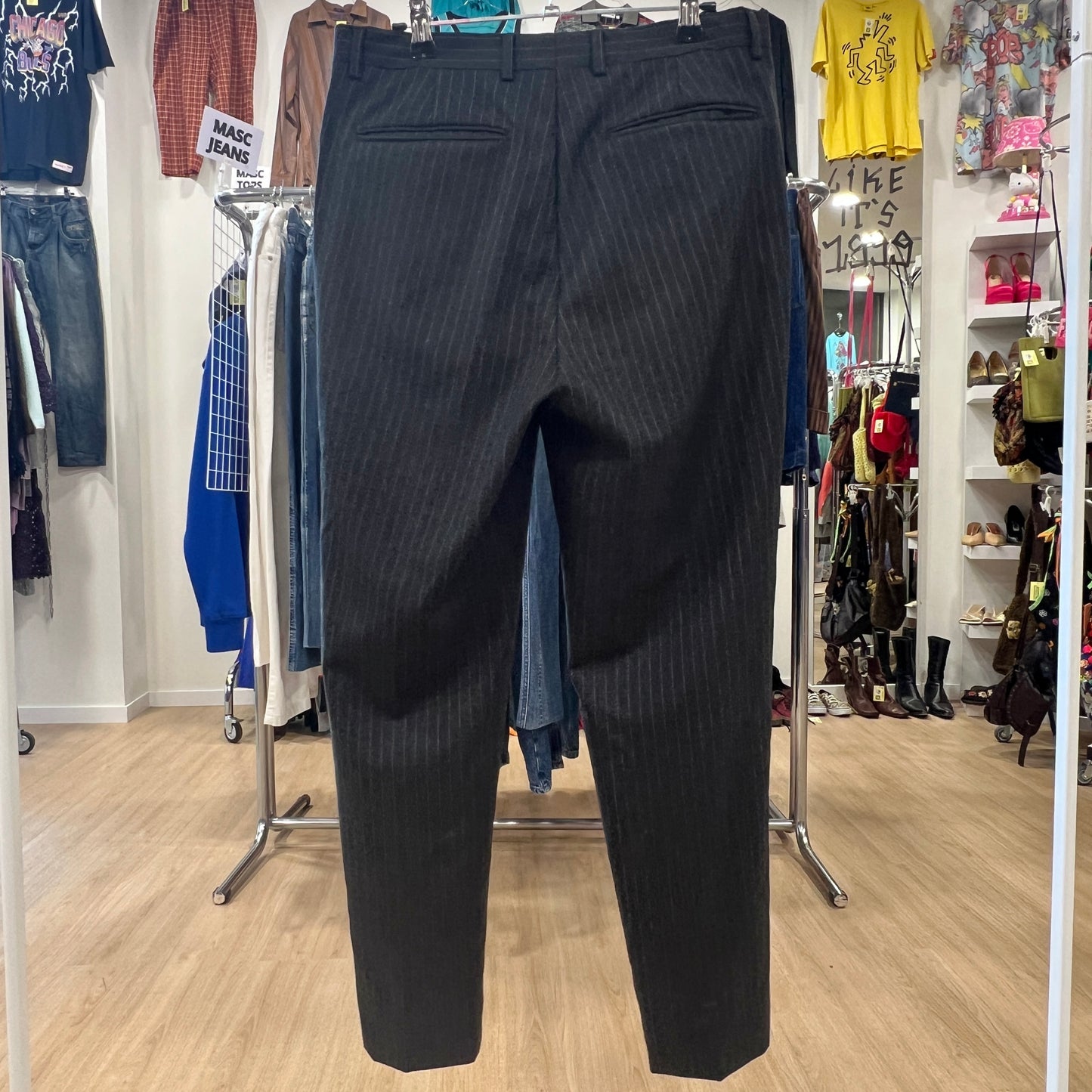 Black pinstripe pants displayed in a clothing store with various items in the background
