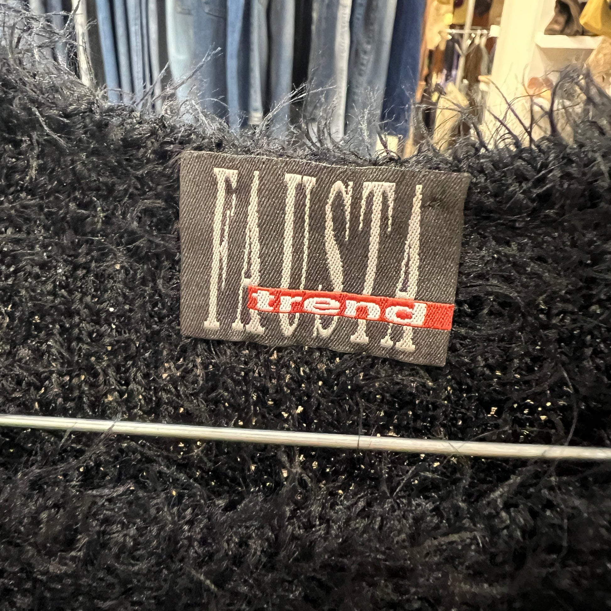 Black textured fabric with a 'Fausta trend' label on a blurred background