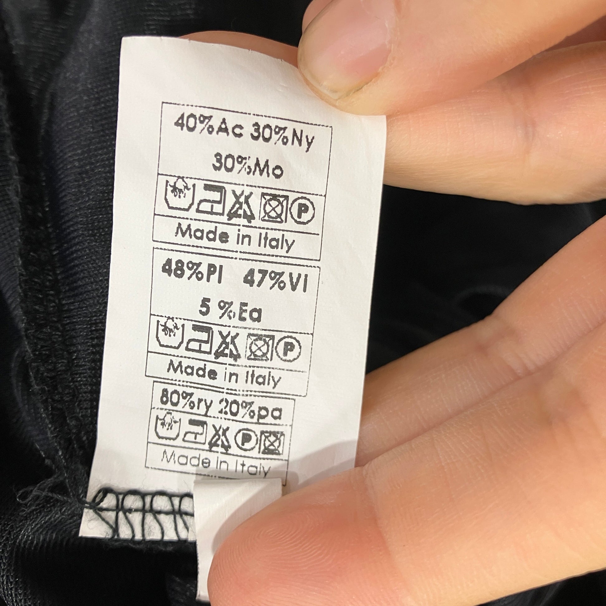 Clothing label with fabric composition and care instructions held by a hand