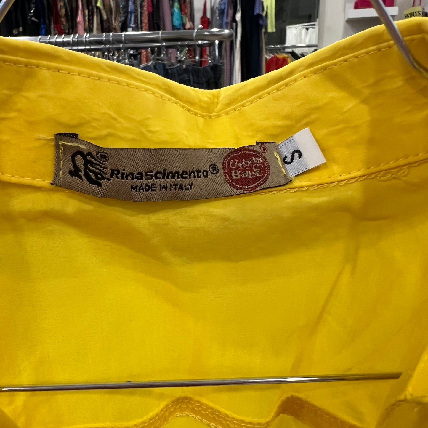 Close-up of a yellow garment with a label in a clothing store setting