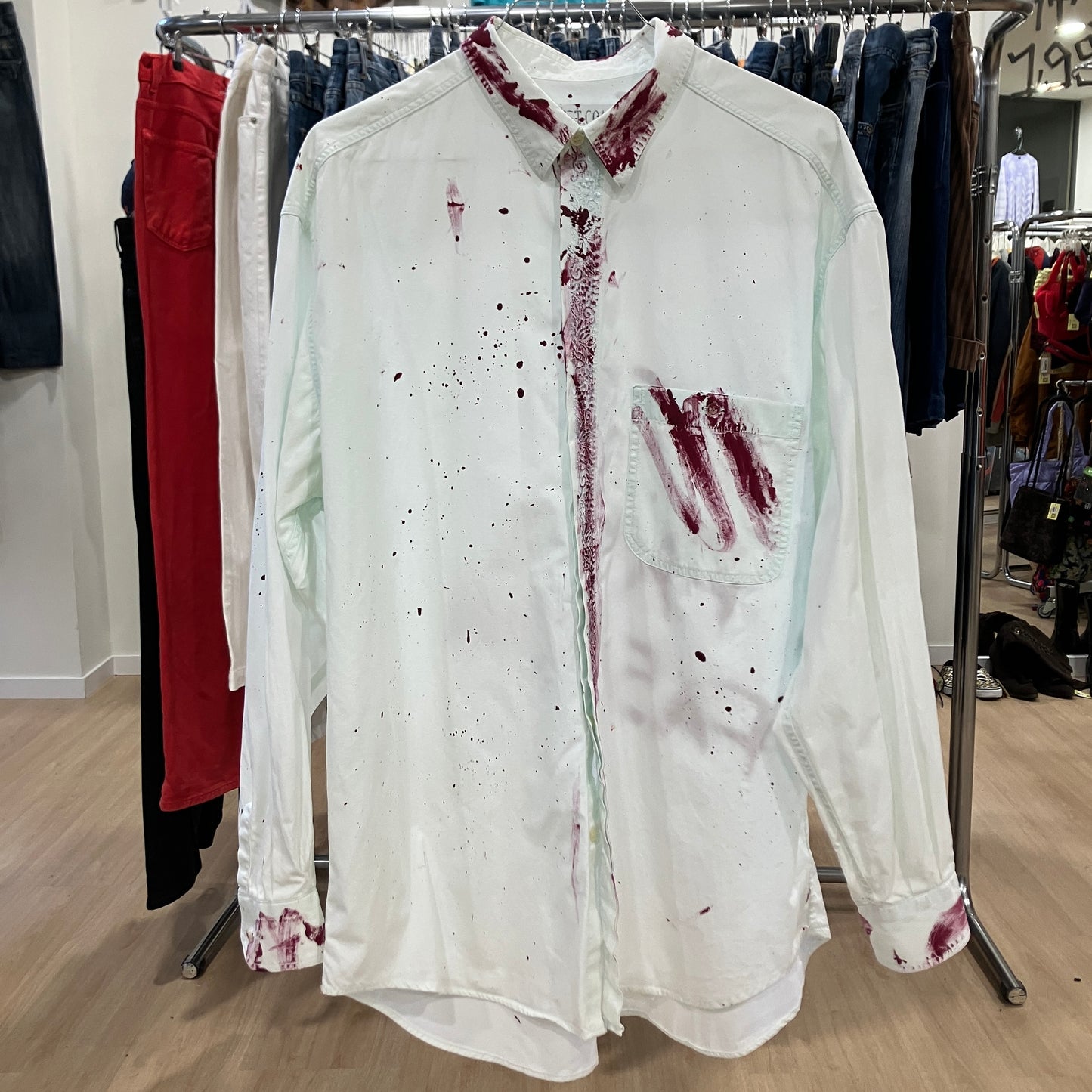 White shirt with red stains on a rack in a store setting