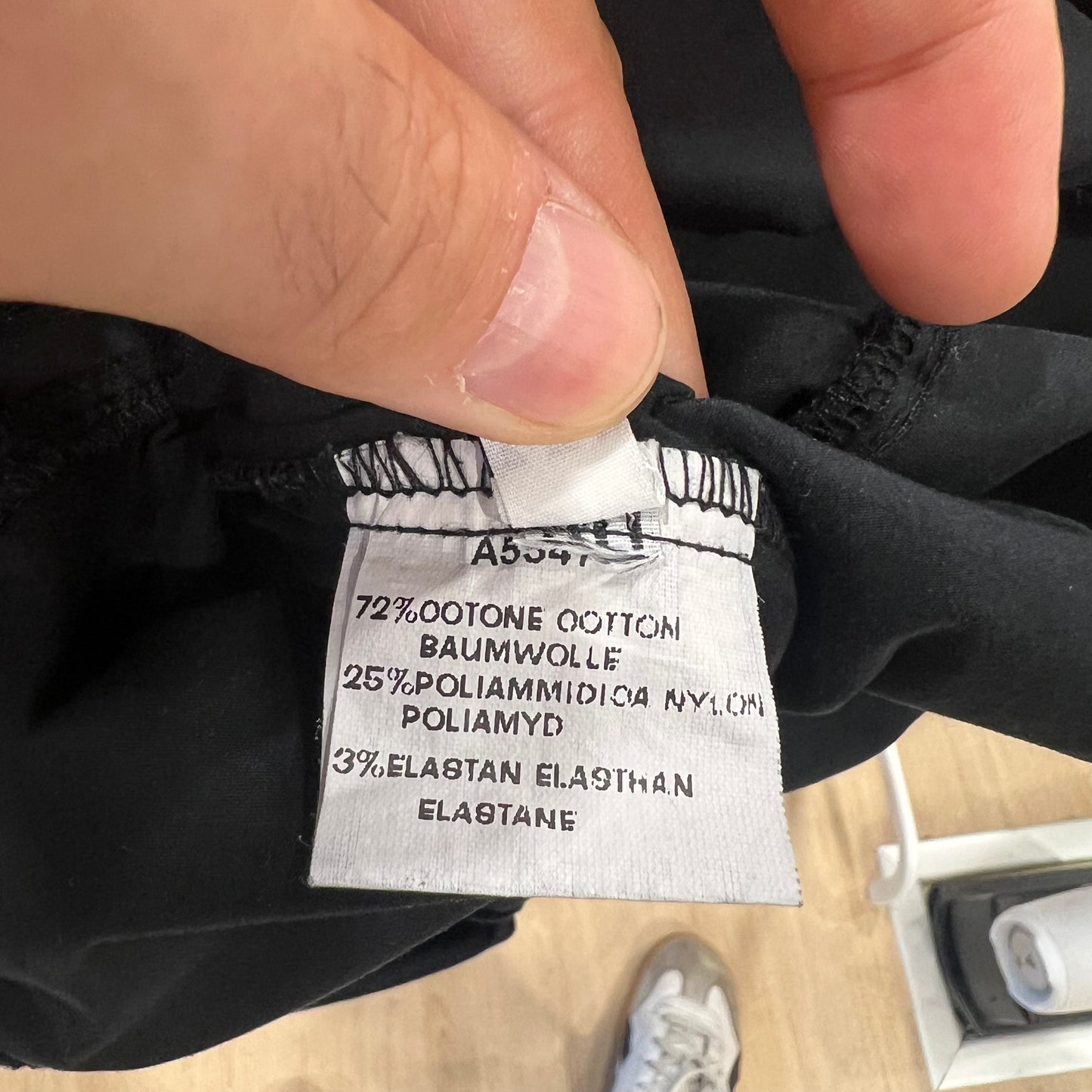 Clothing label with fabric composition details held by a hand on a blurred background