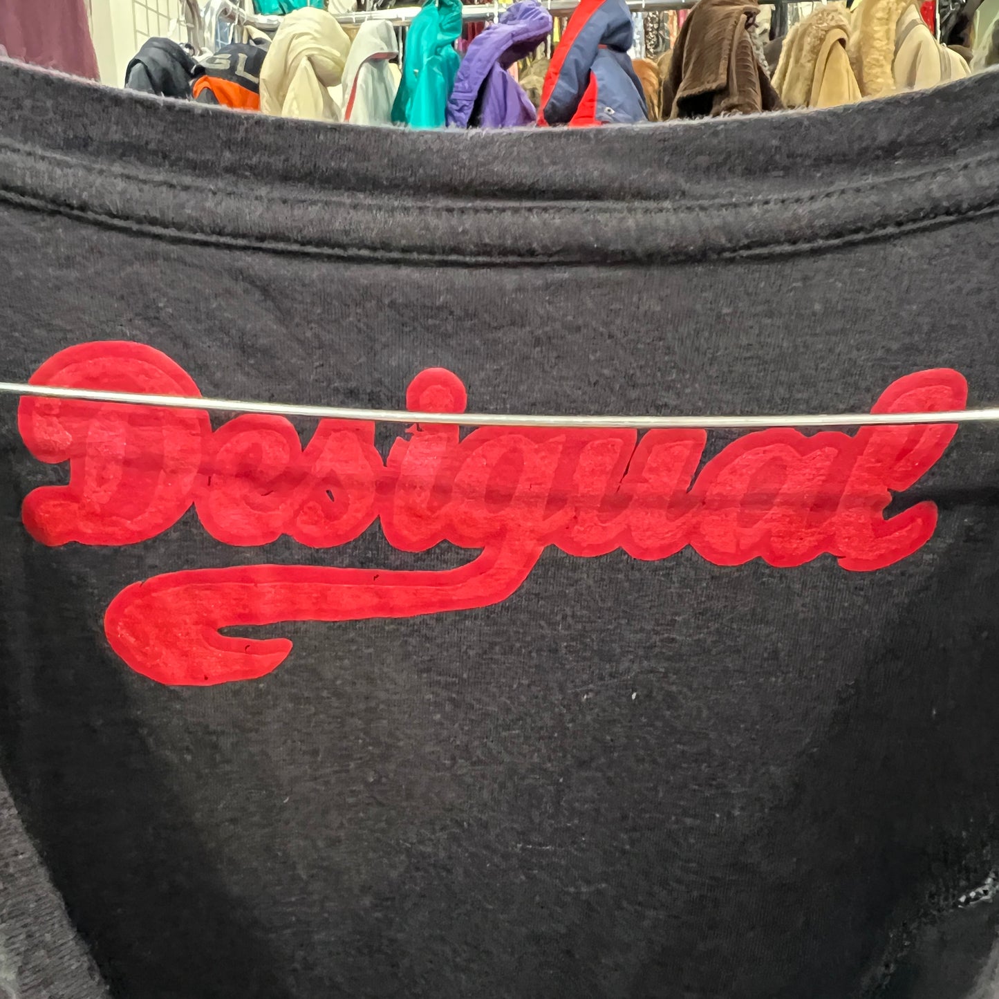 Black dress with red 'Desigual' logo in a clothing store setting