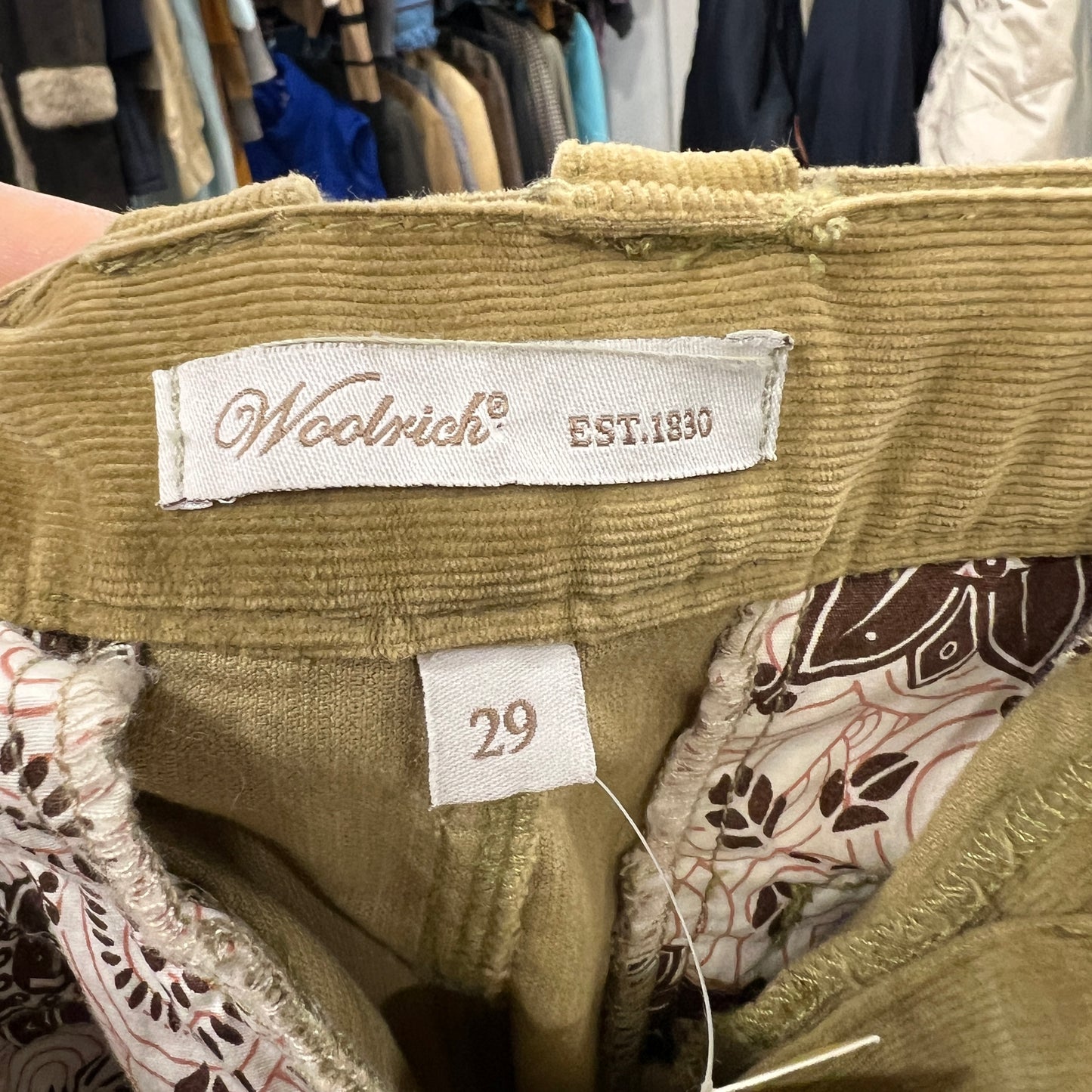 Close-up of a camel corduroy skirt with a Woolrich label and size tag