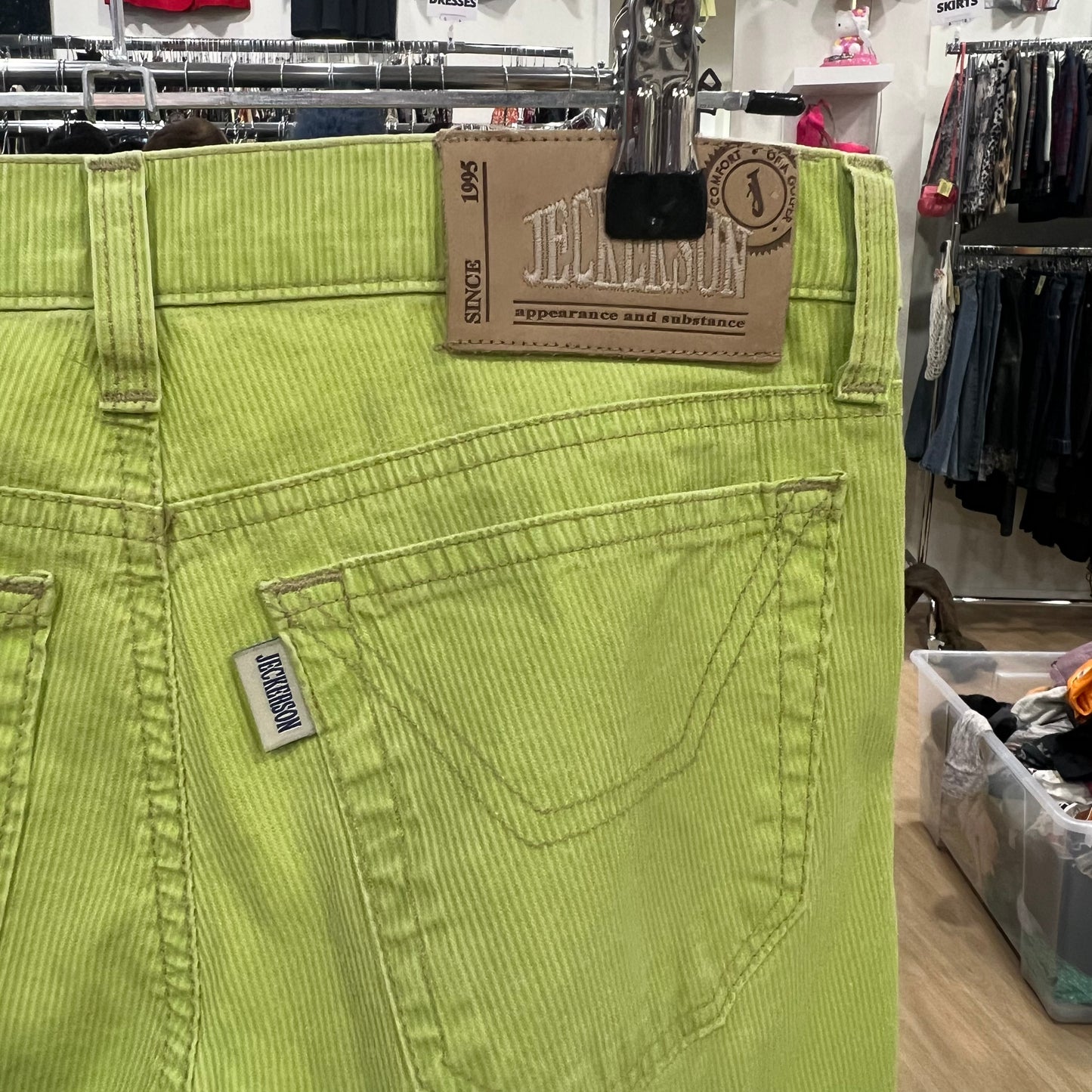 Green pants with a brand tag on a rack in a store setting