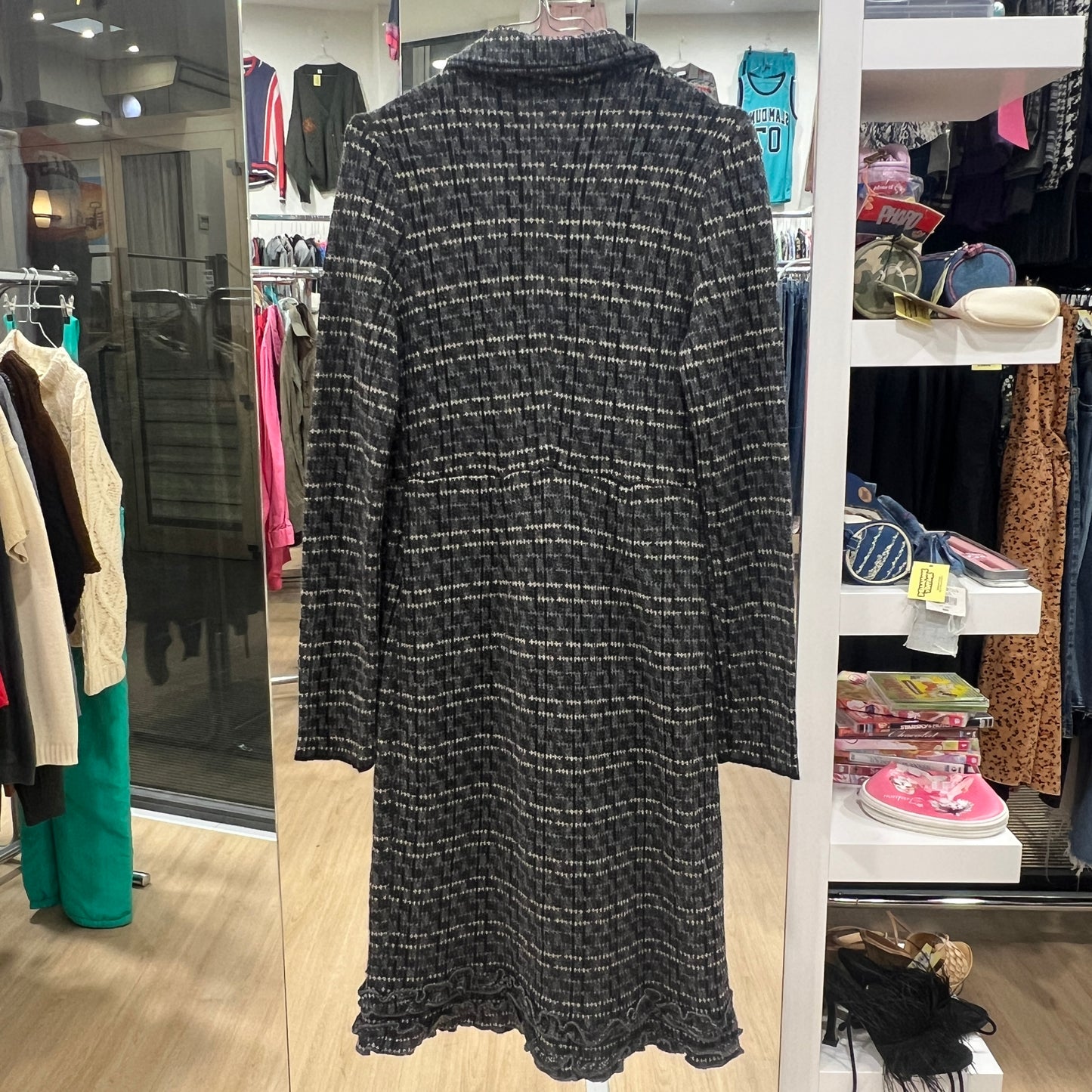 Black patterned dress in a store setting with shelves and other clothing in the background